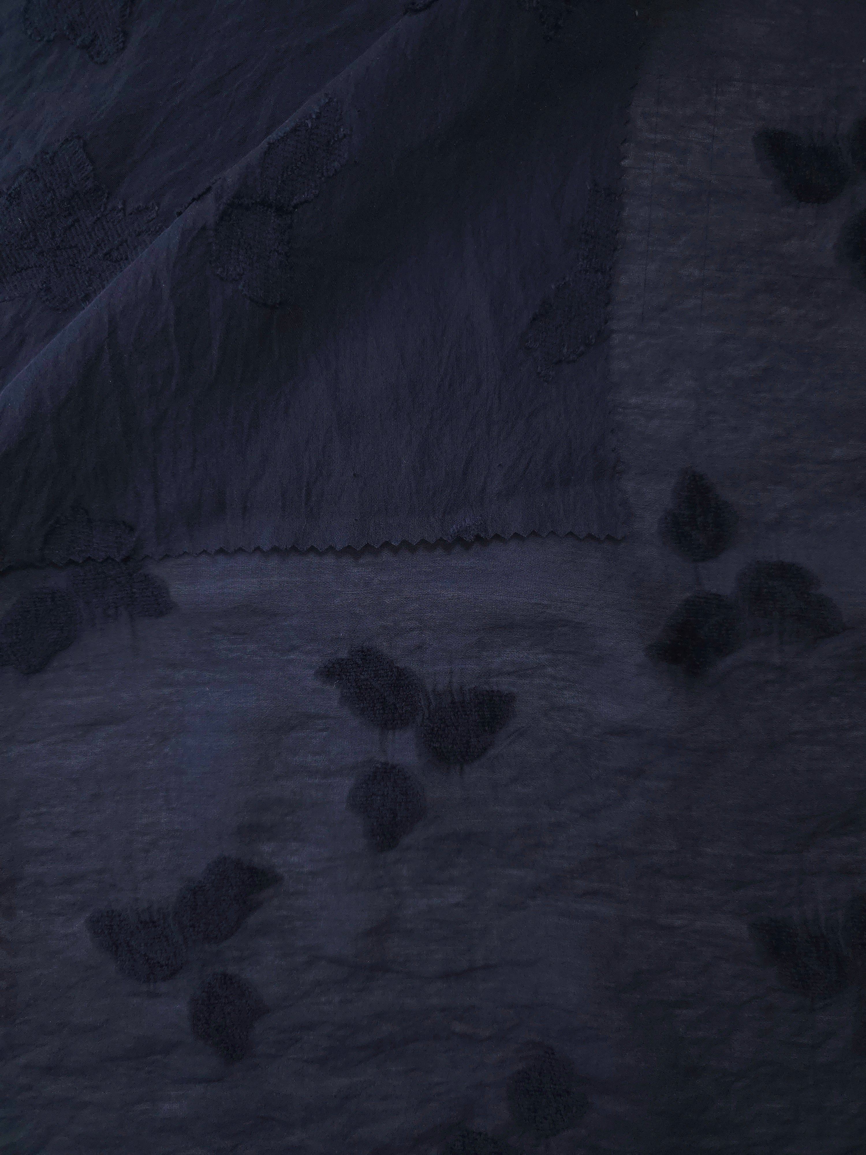 Wide view of dark blue small leaf embossed viscose jacquard fabric with raised motif.