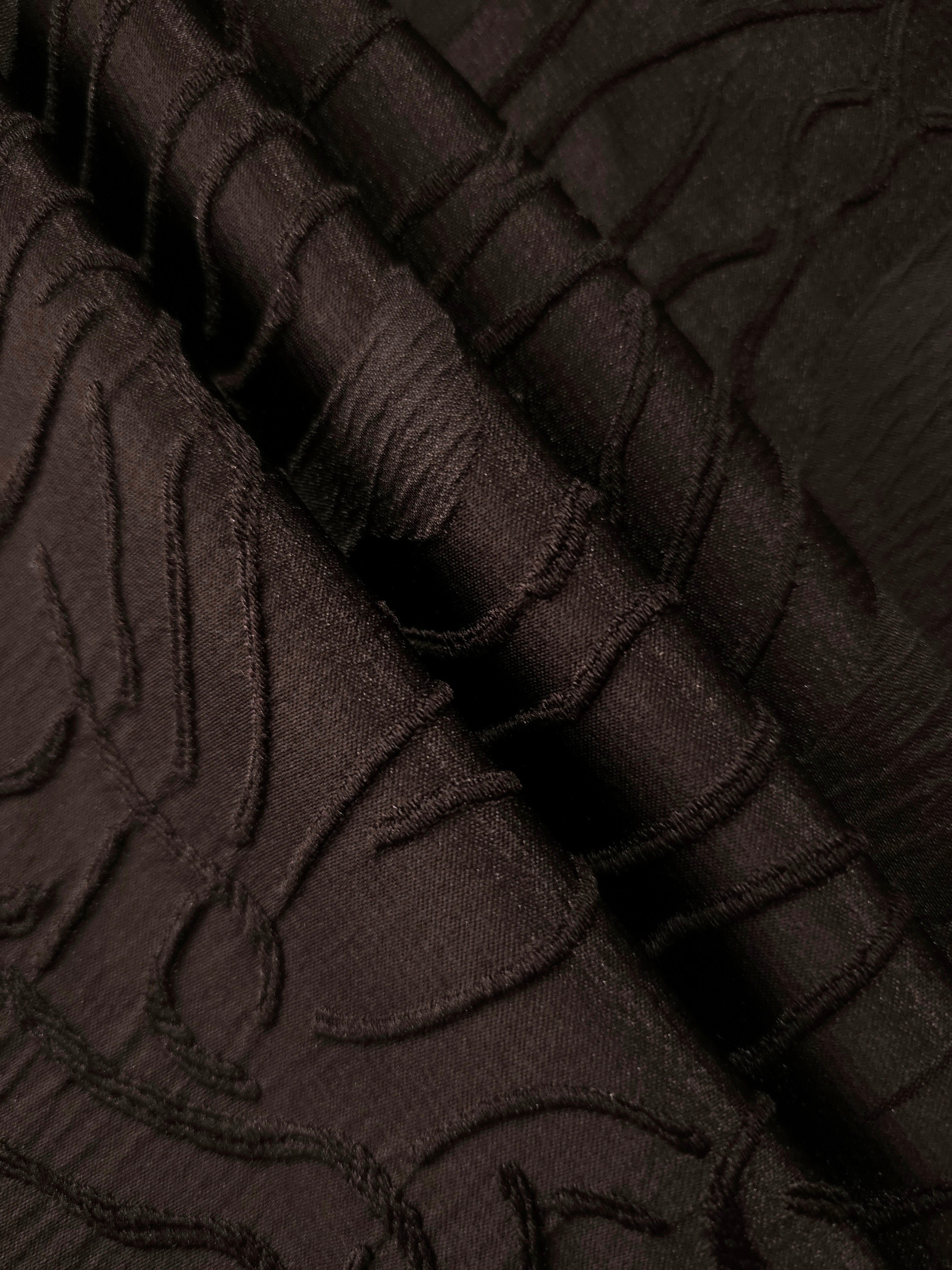 Pattern detail of brown laurel polyester crepe jacquard fabric with raised woven texture.