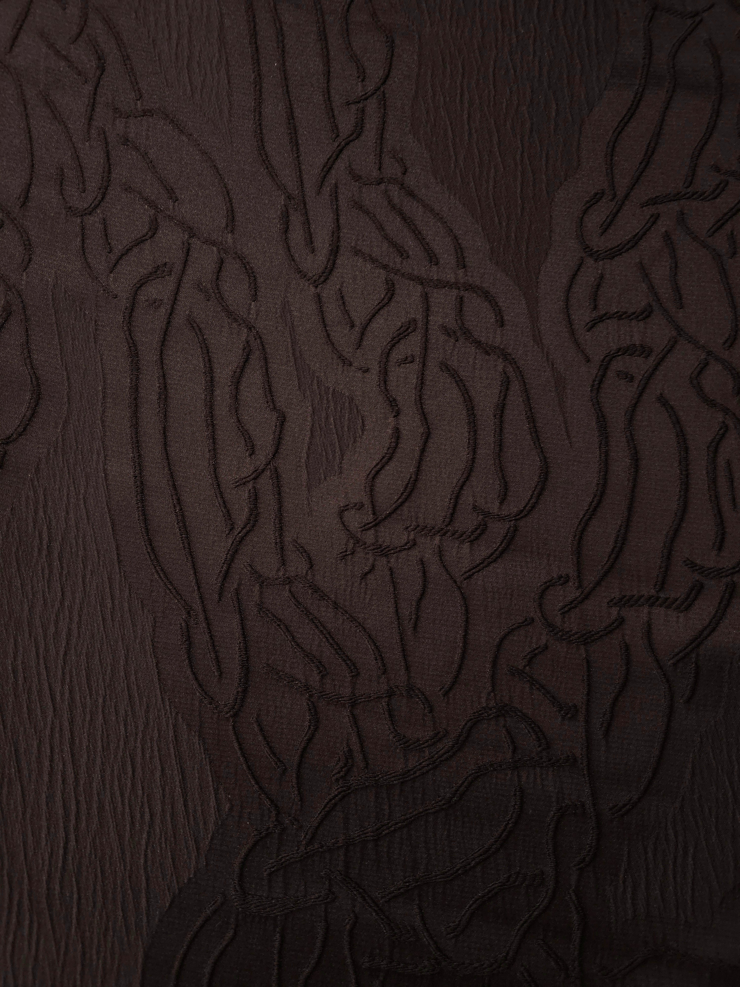 Closeup texture of brown laurel polyester crepe jacquard fabric for structured dress layers.