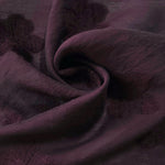Swirl drape of dark burgundy flower embossed viscose jacquard fabric for overlays.
