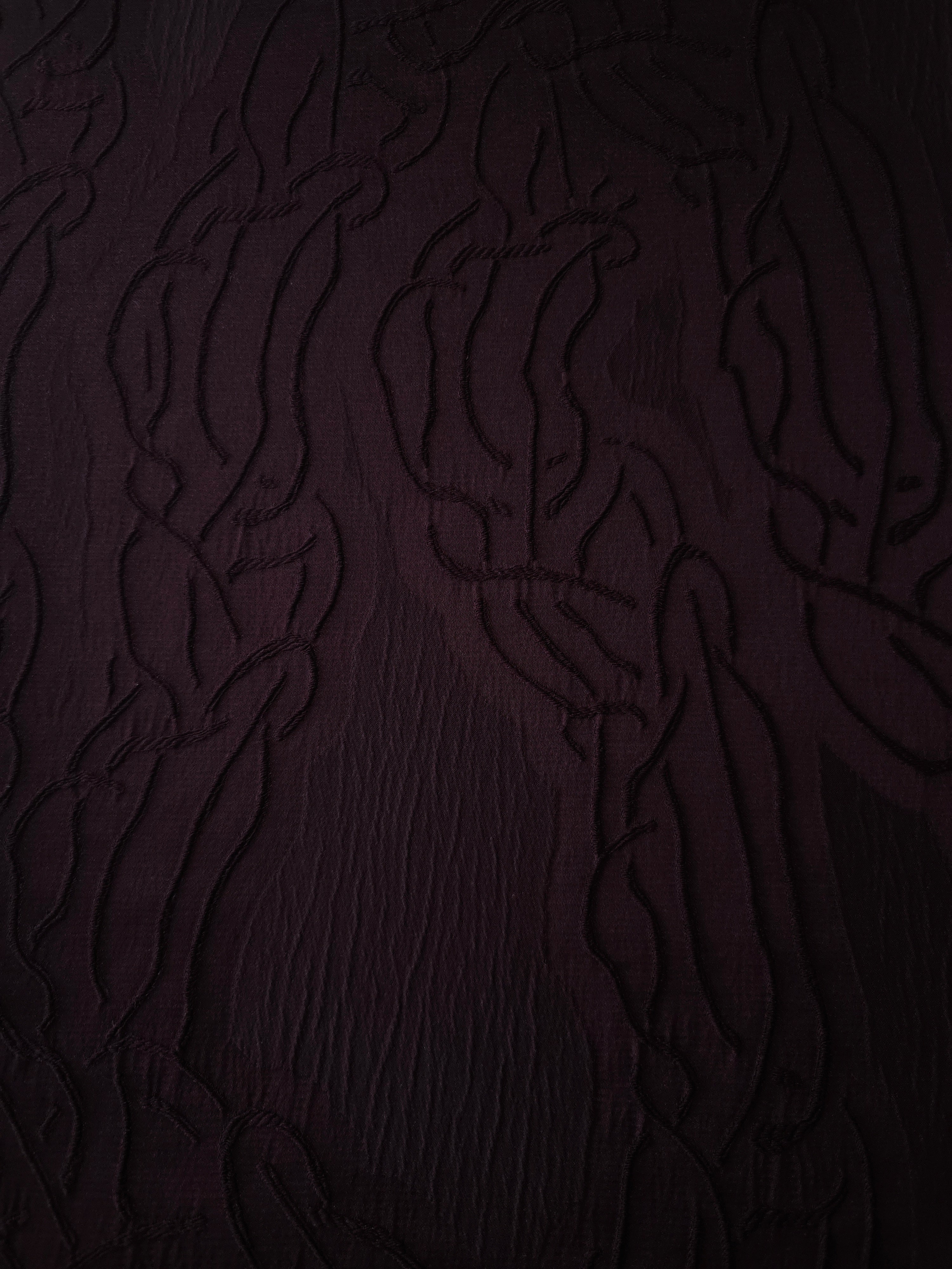 Full view of burgundy laurel polyester crepe jacquard fabric with tonal raised motif.