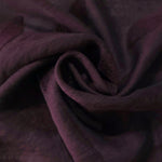 Swirl drape of dark burgundy leaf embossed viscose jacquard fabric for layered garments.