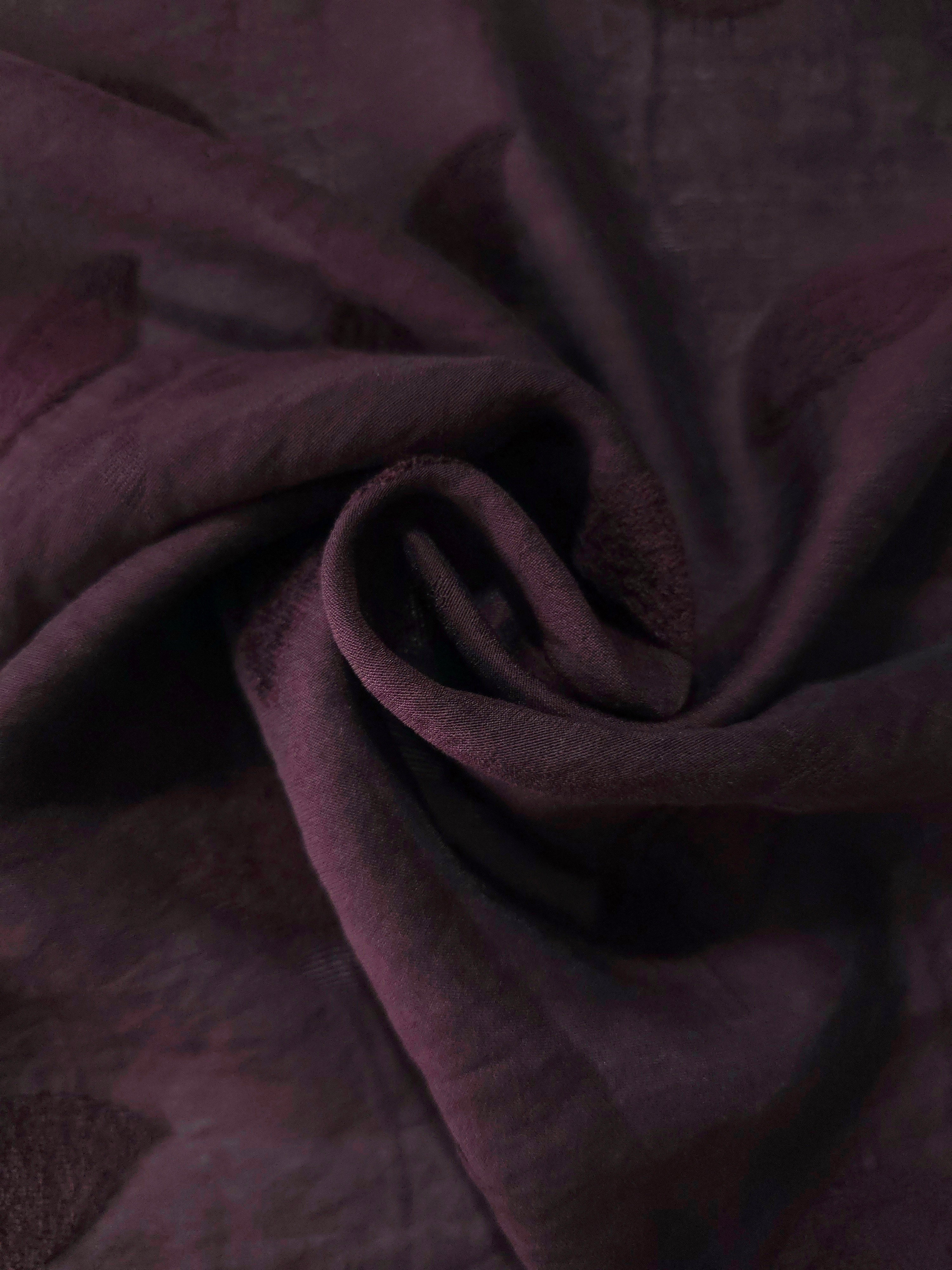 Swirl drape of dark burgundy leaf embossed viscose jacquard fabric for layered garments.
