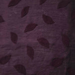 Drape view of dark burgundy leaf embossed viscose jacquard fabric for dresses and overlays.