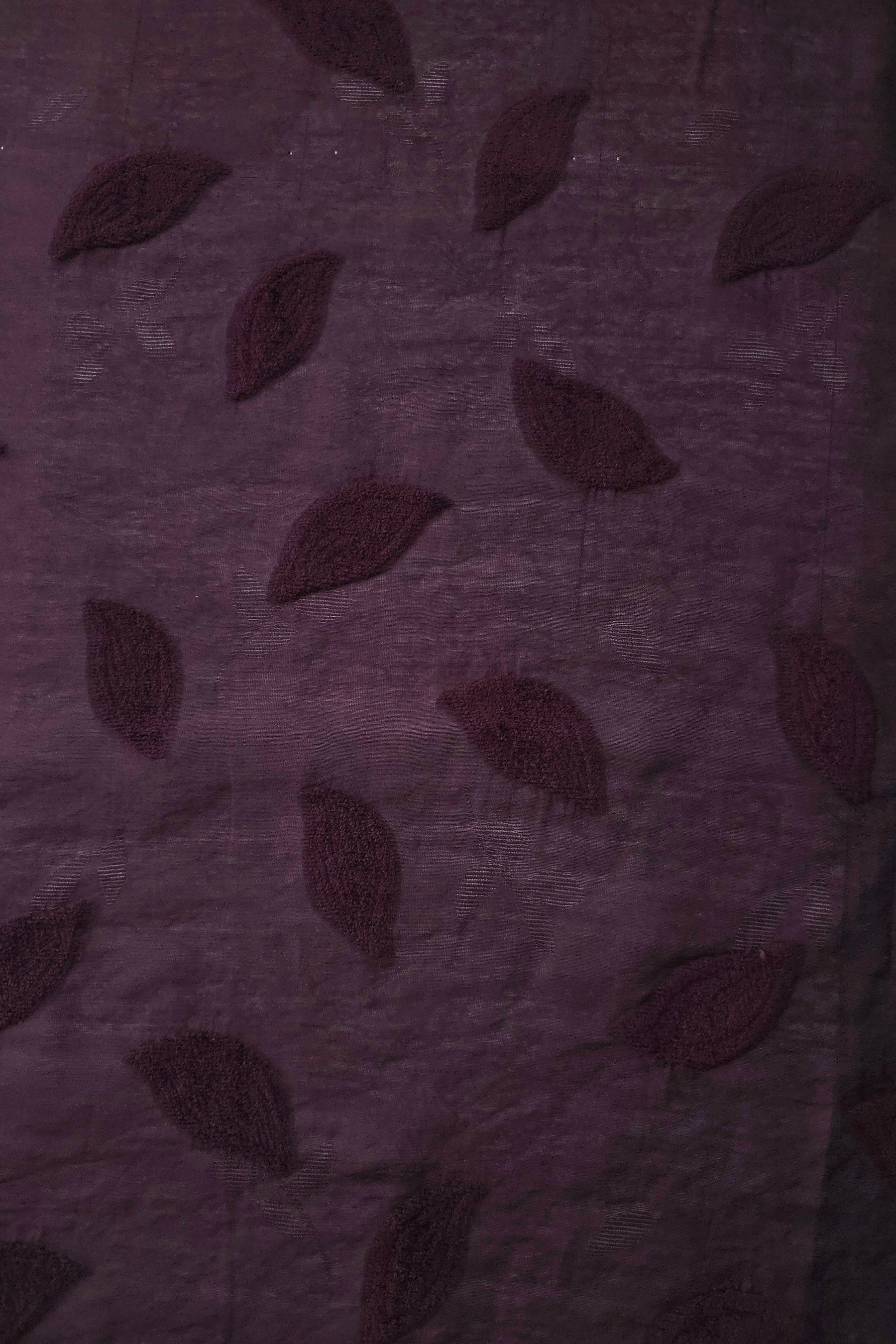 Drape view of dark burgundy leaf embossed viscose jacquard fabric for dresses and overlays.