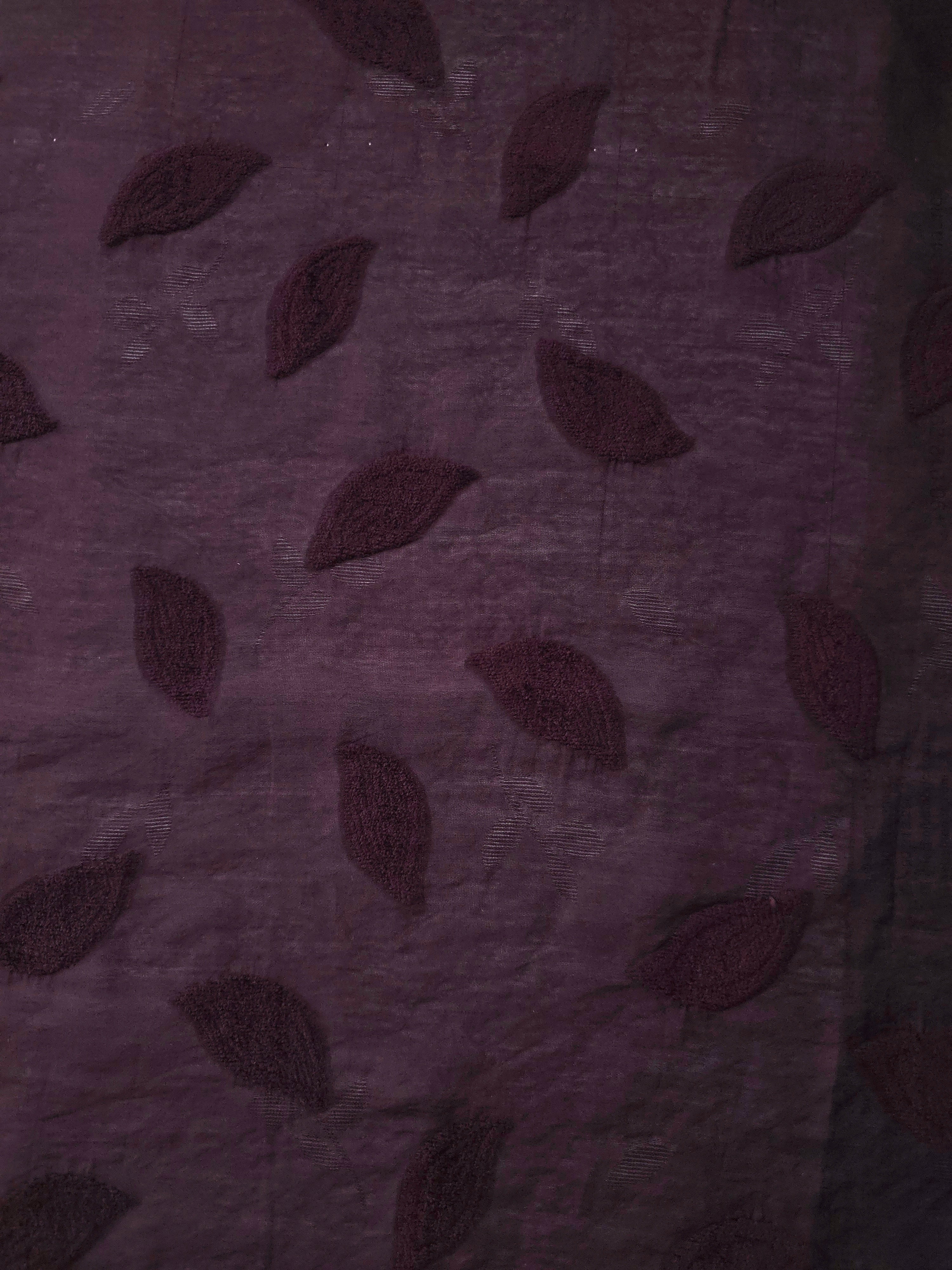 Drape view of dark burgundy leaf embossed viscose jacquard fabric for dresses and overlays.