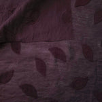Wide view of dark burgundy leaf embossed viscose jacquard fabric with tonal raised texture.