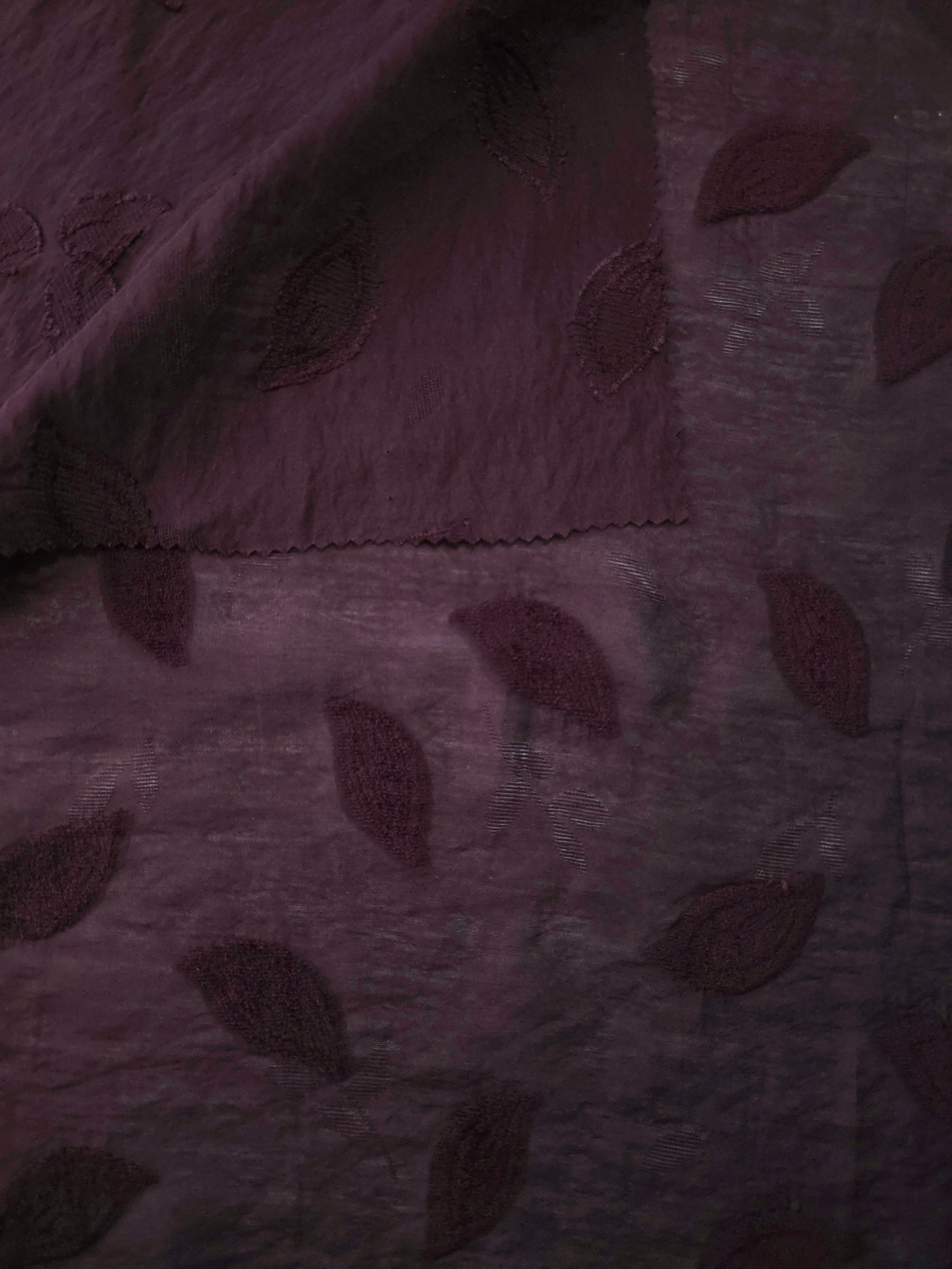 Wide view of dark burgundy leaf embossed viscose jacquard fabric with tonal raised texture.