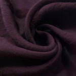 Dark burgundy small leaf embossed viscose jacquard fabric in a close draped view.