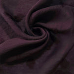Swirl drape of dark burgundy small leaf embossed viscose jacquard fabric for overlays.