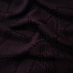 Closeup texture of burgundy wheat leaf polyester crepe jacquard fabric for structured garments.