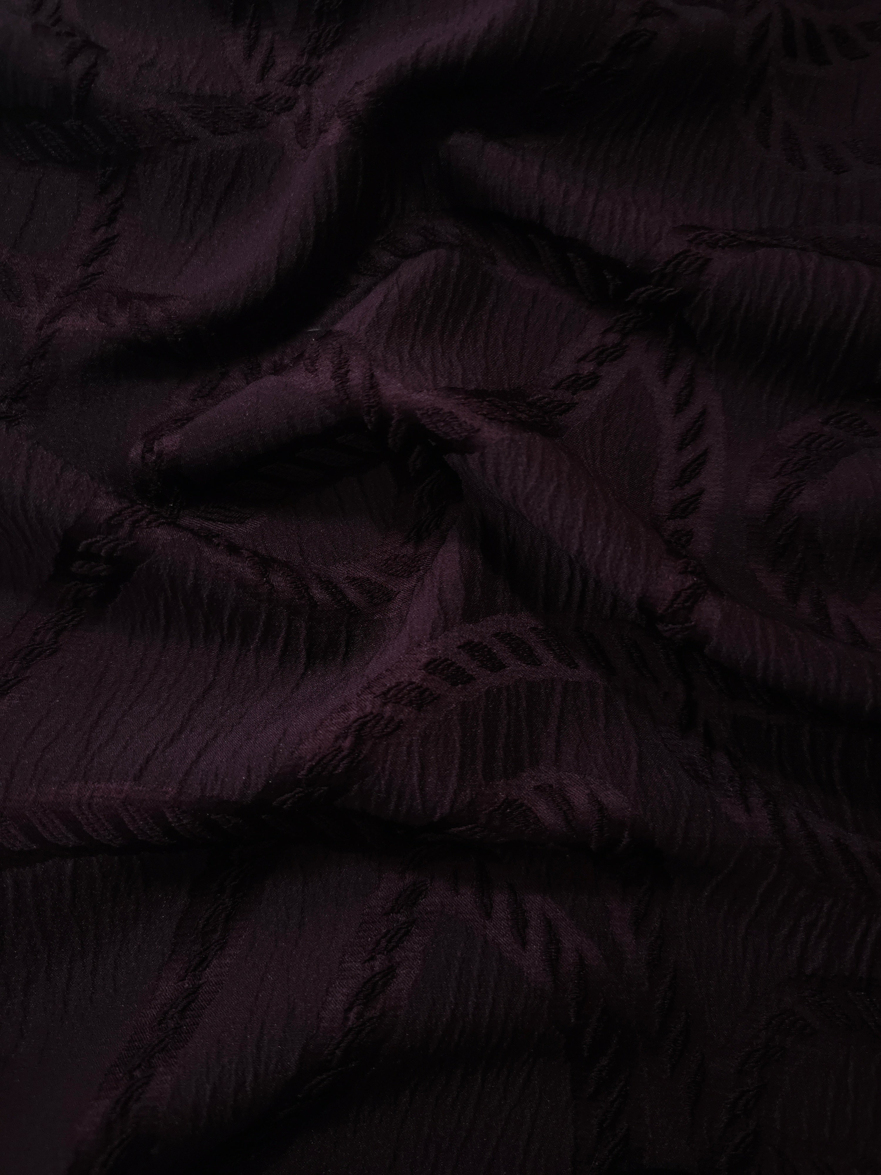 Closeup texture of burgundy wheat leaf polyester crepe jacquard fabric for structured garments.