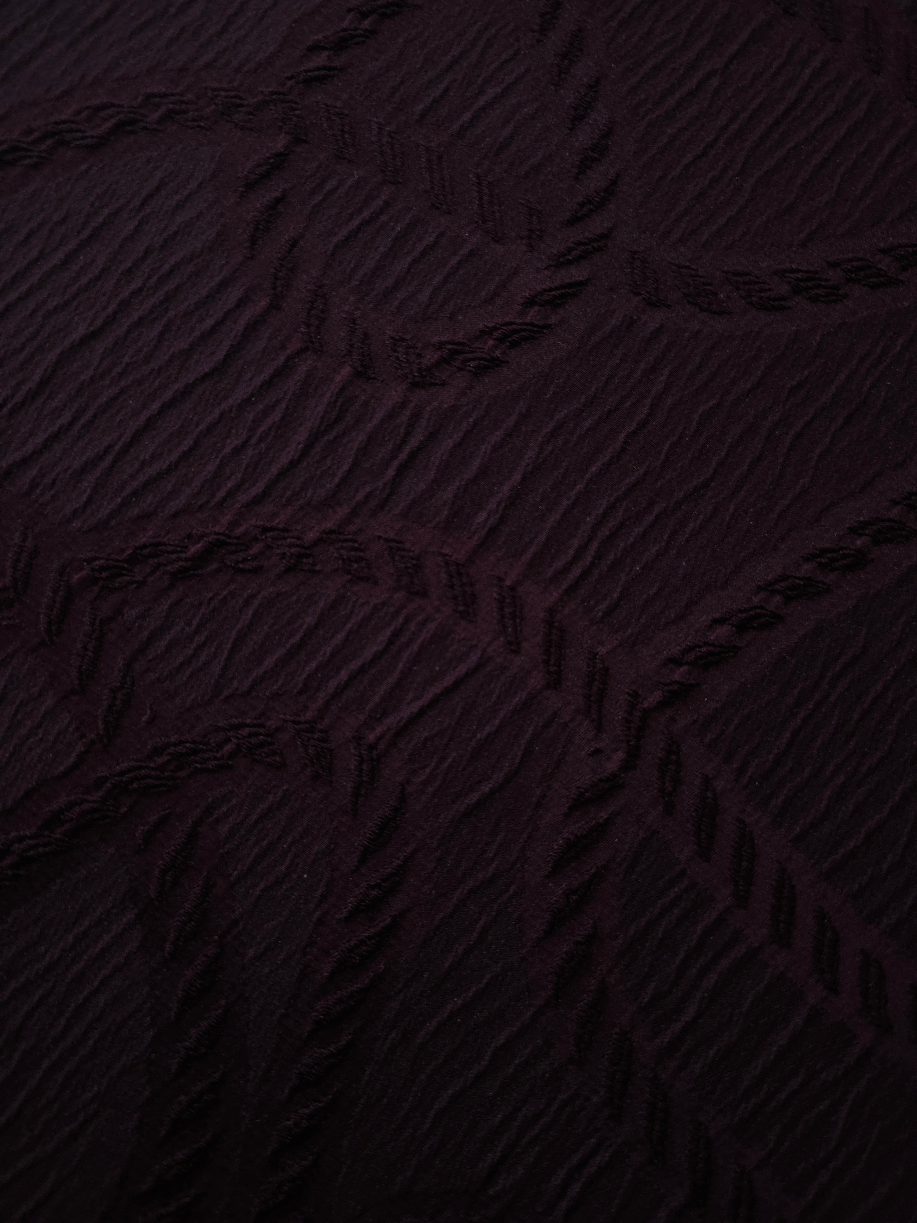 Full view of burgundy wheat leaf polyester crepe jacquard fabric with tonal raised motif.