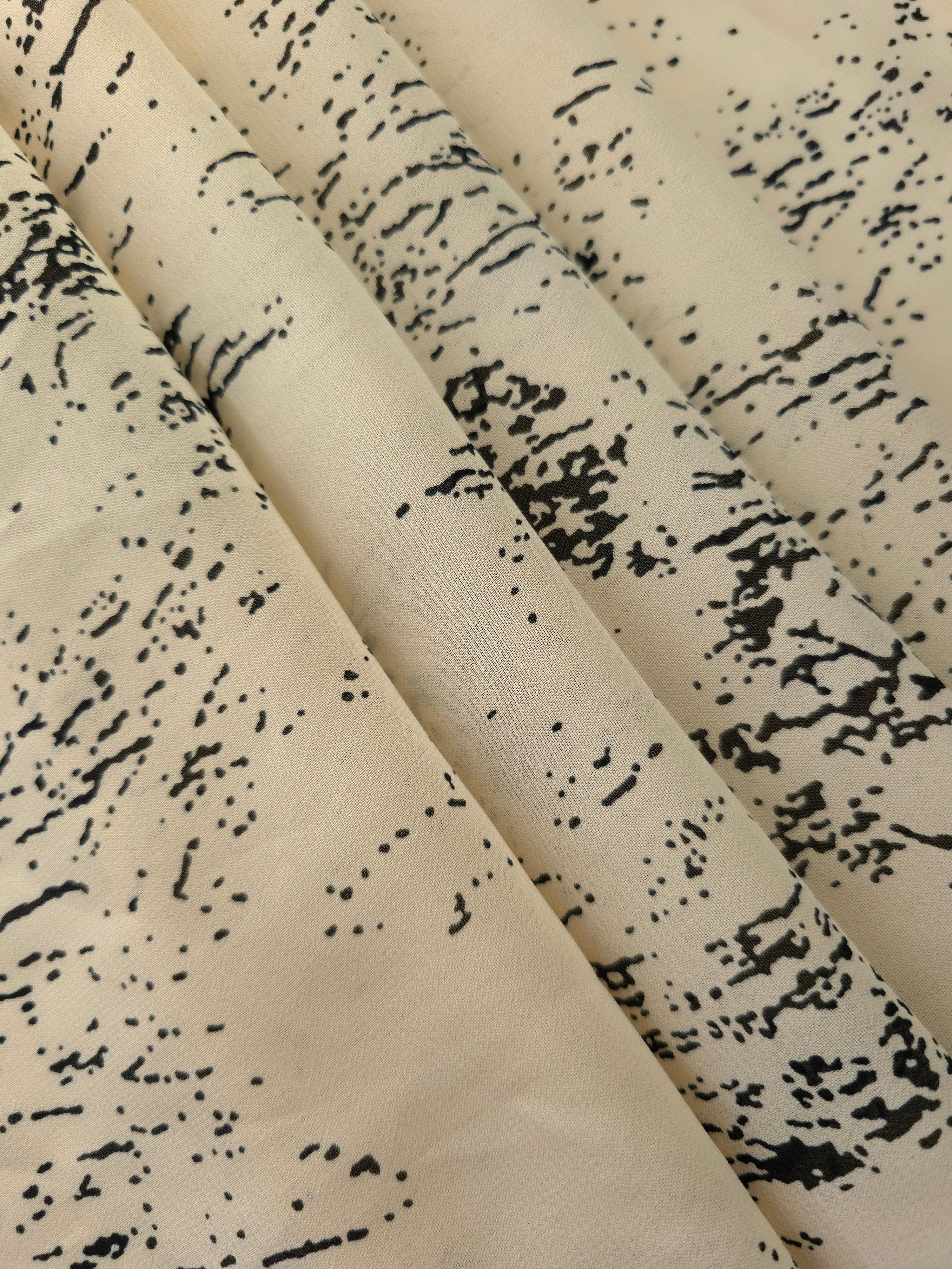 Folded black rayon chiffon Empirme with graphic print for dresses and blouse layers.