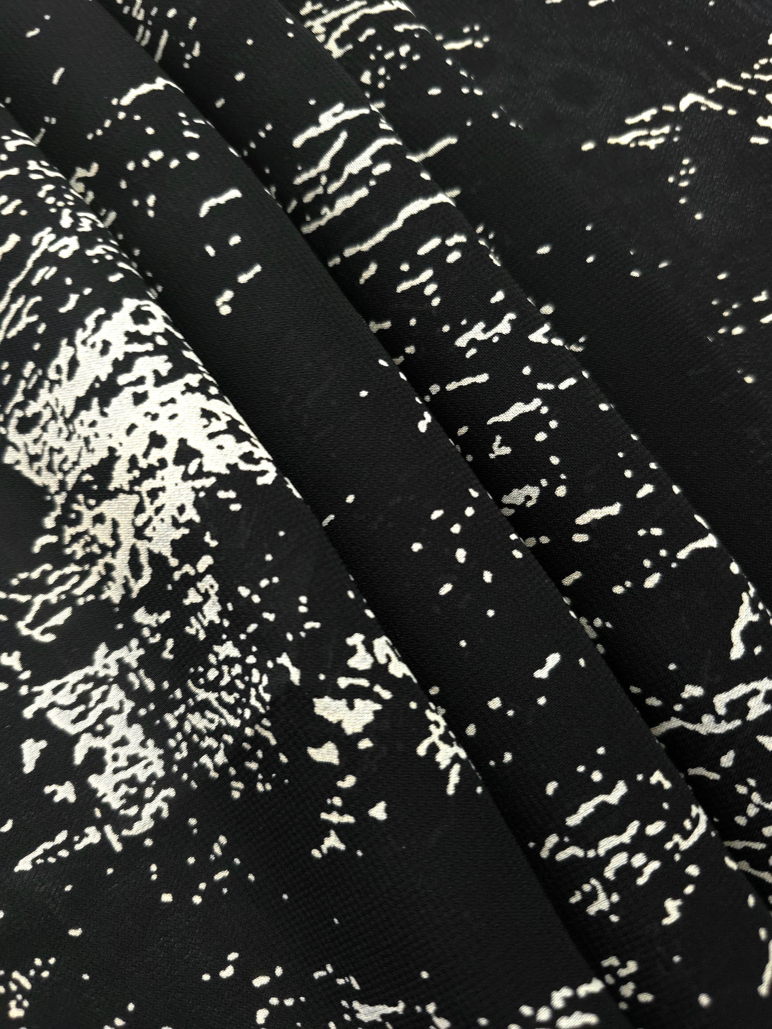 Folded white rayon chiffon Empirme with graphic print for lined dress layers.