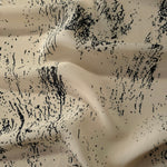 Wave fold of black rayon Empirme fabric with graphic print for fluid dressmaking.