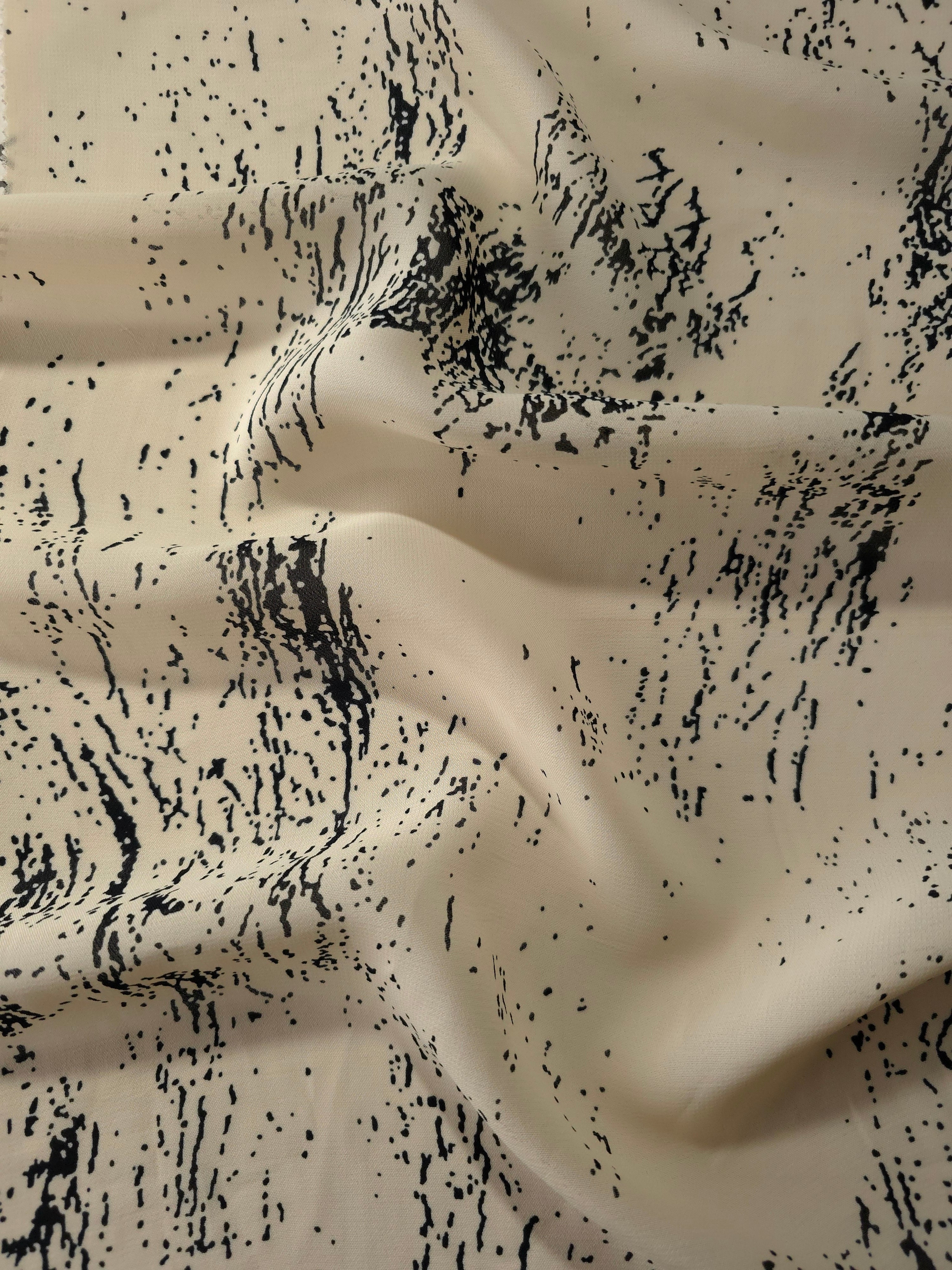 Wave fold of black rayon Empirme fabric with graphic print for fluid dressmaking.