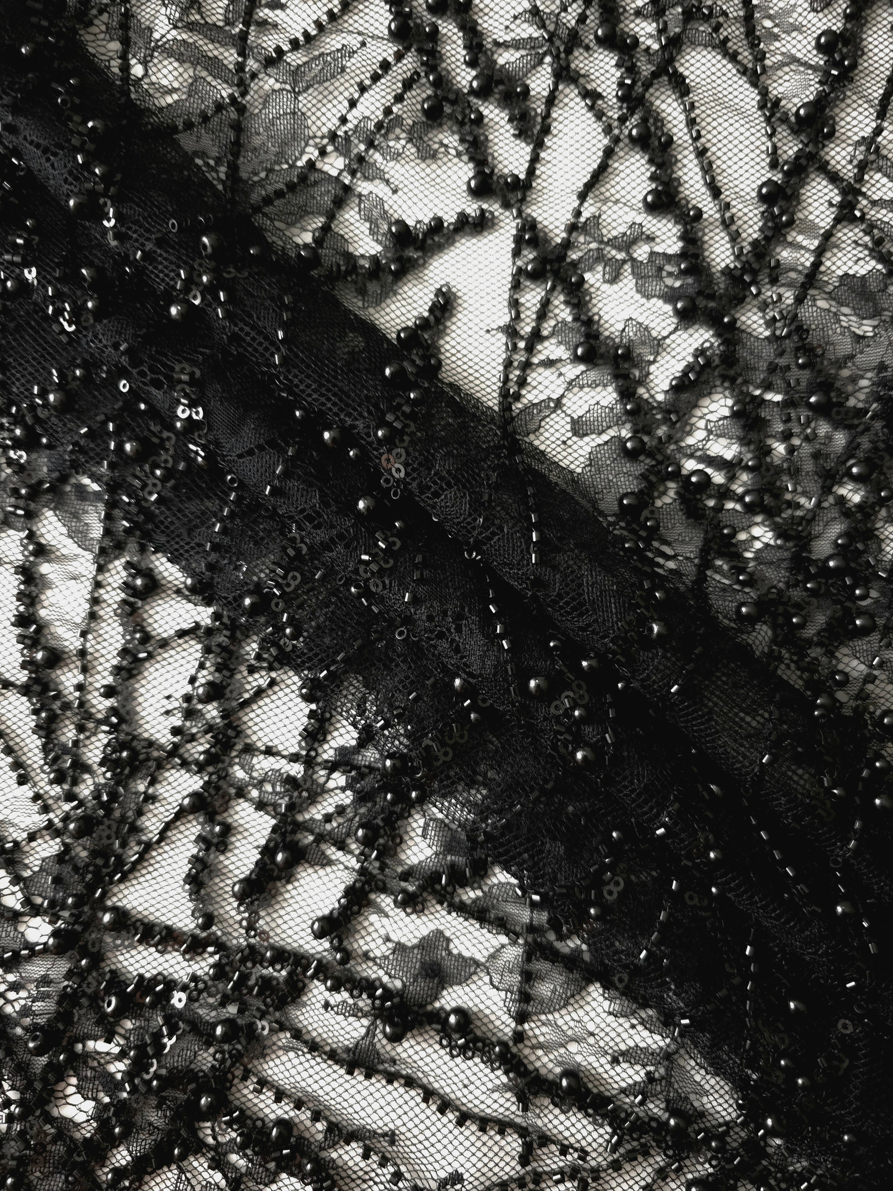 Close-up of Jet Black Botanical Pearl beaded lace showing textured black occasionwear lace, with branching botanical vines with pearl-like beading.