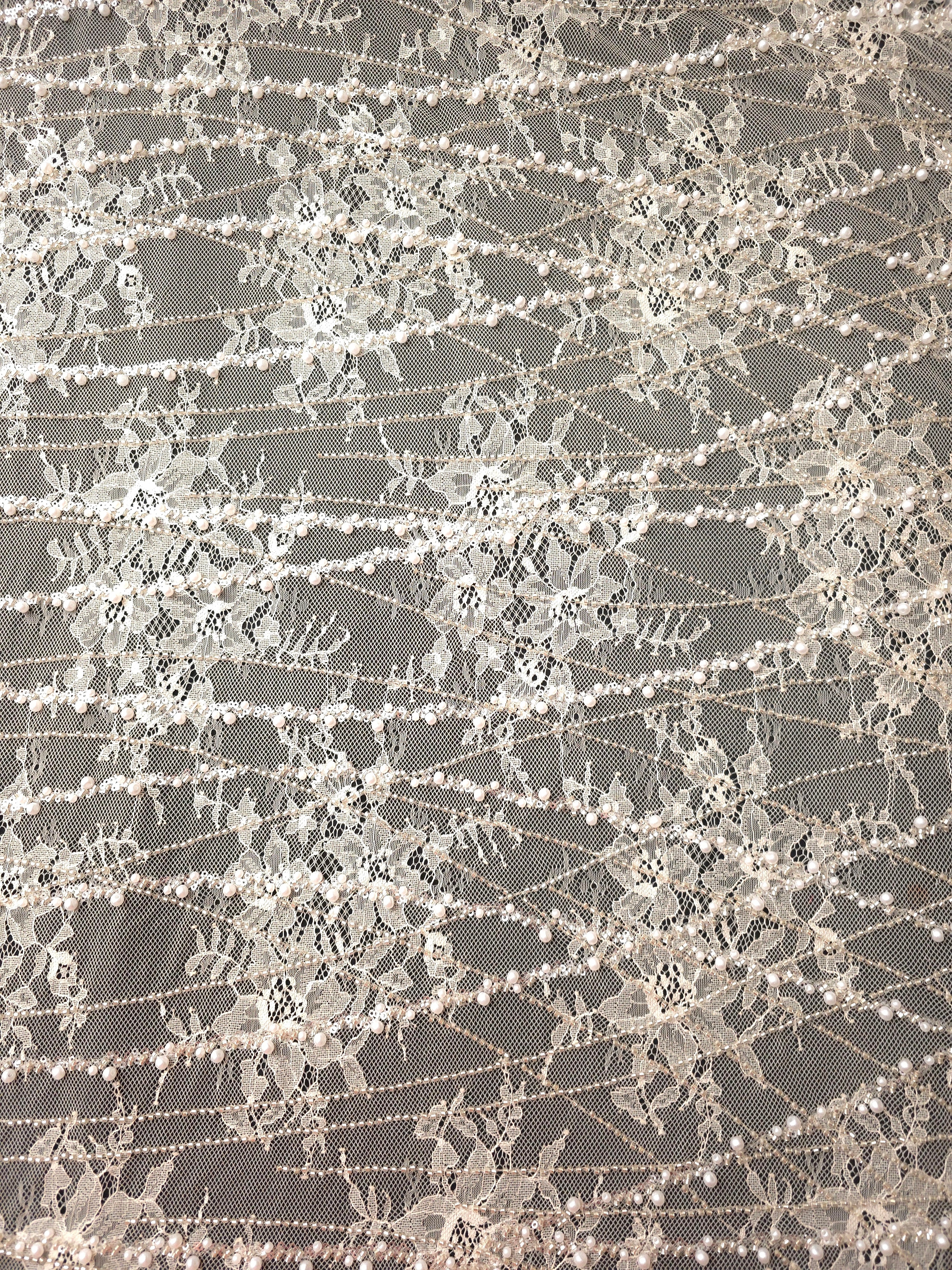 Close-up of Pearl White Botanical Pearl beaded lace showing crystal vine stitching contrast, with branching botanical vines with pearl-like beading.