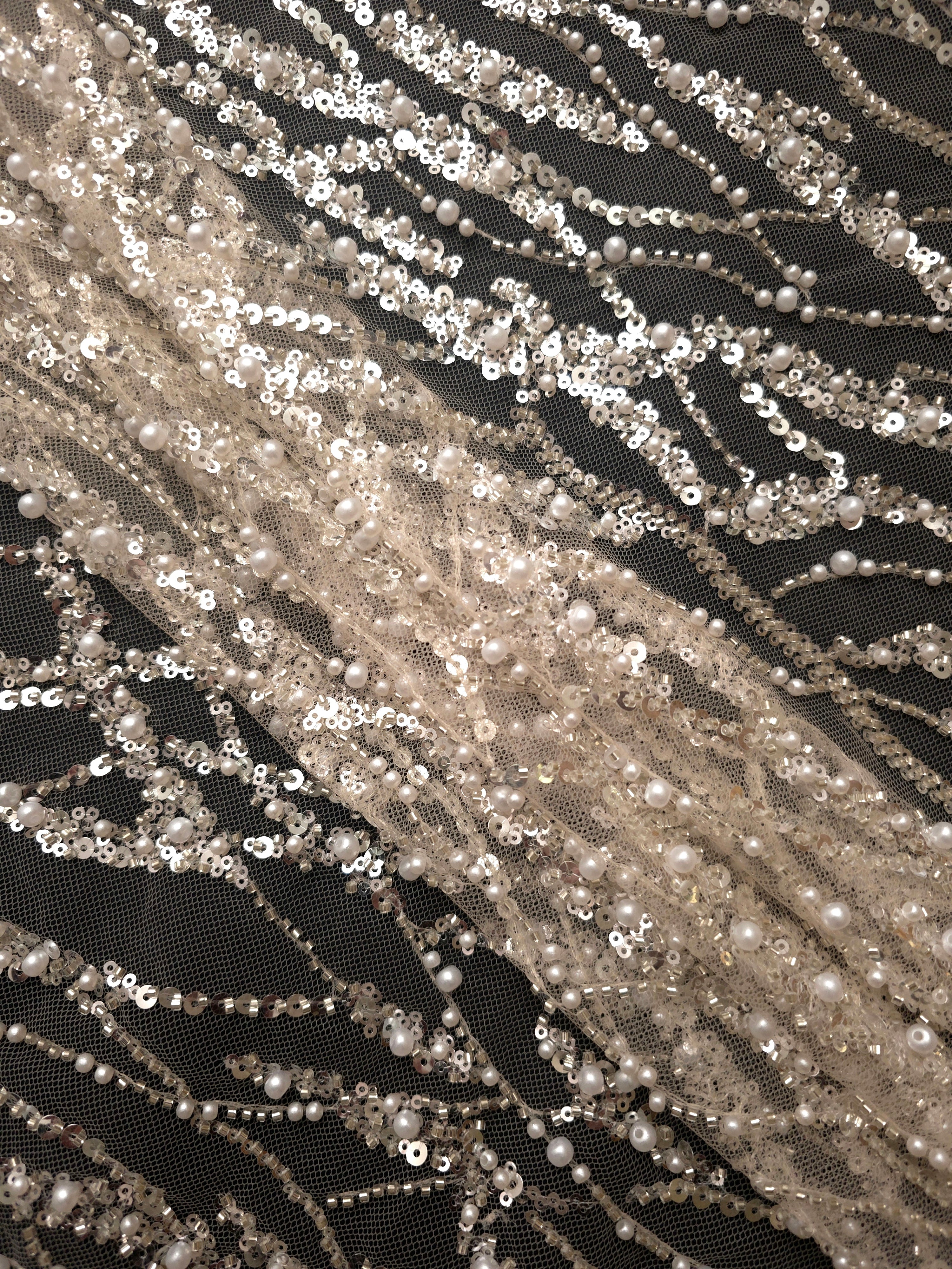 Close-up of Ivory Silver Liquid Wave beaded lace showing raised sequin threadwork macro, with flowing ripples and curved sequin embellishment.