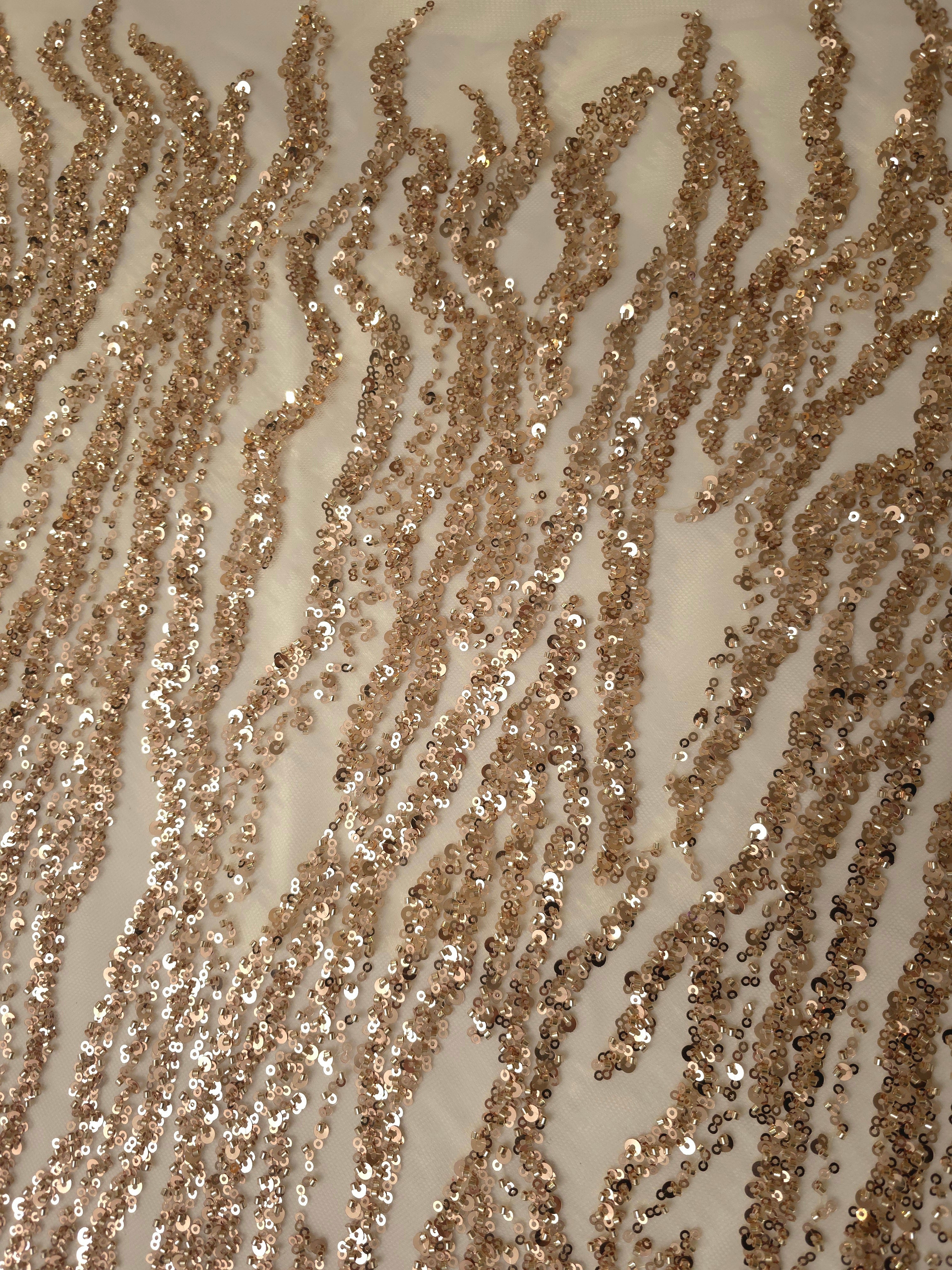 Close-up of fine taupe sequin linework with irregular embroidered curves and transparent net between bands.