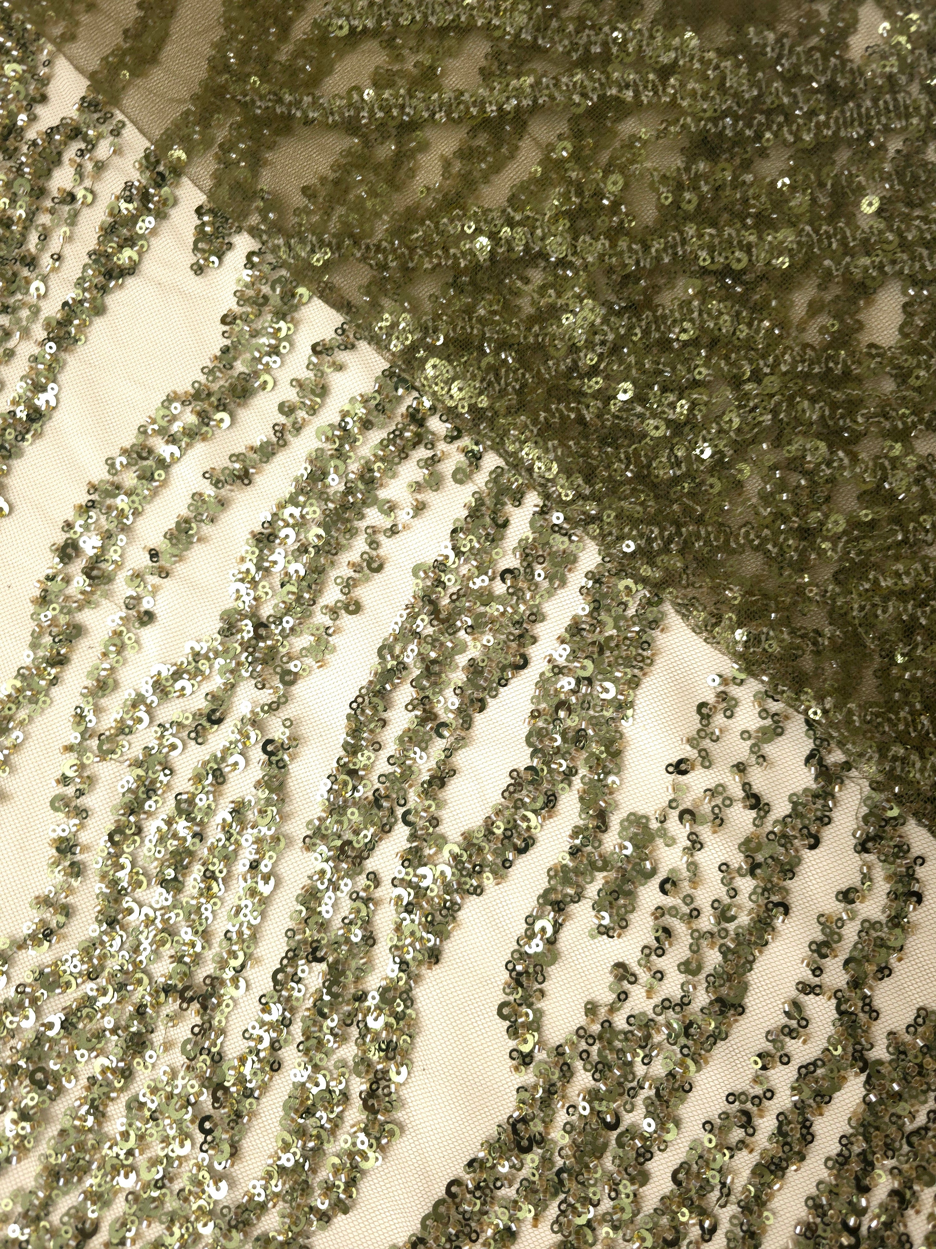 Olive beaded embroidery photographed with exposed sheer mesh, showing dense decorative lines against open fabric.