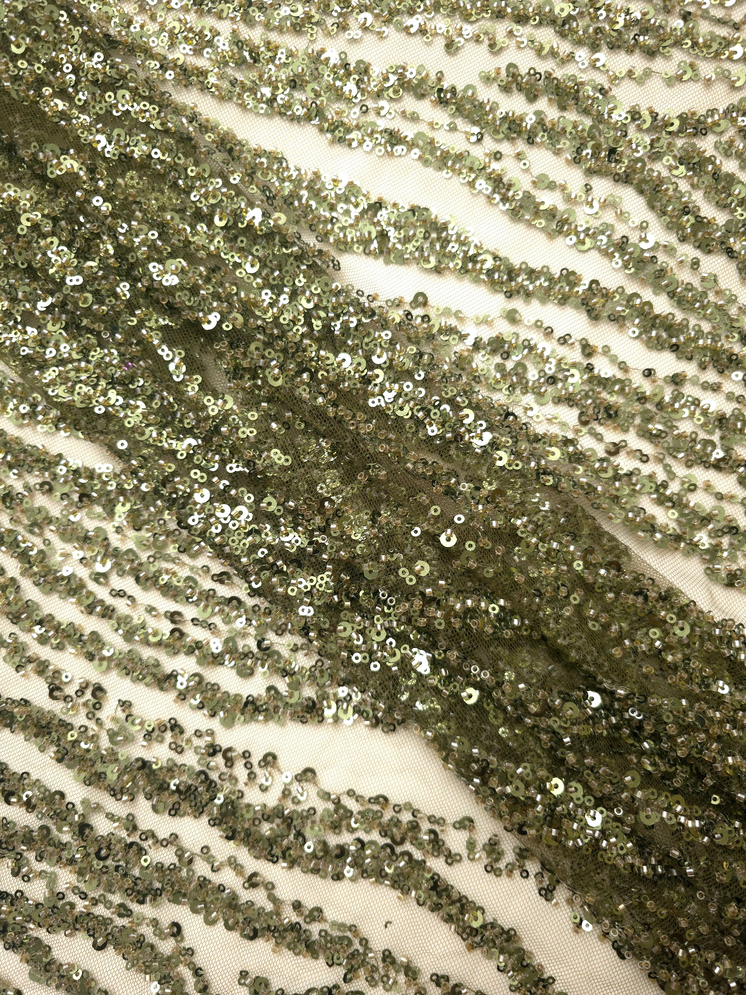 Macro image of metallic olive bead-and-sequin embroidery, detailing raised texture and irregular zebra-style lines.