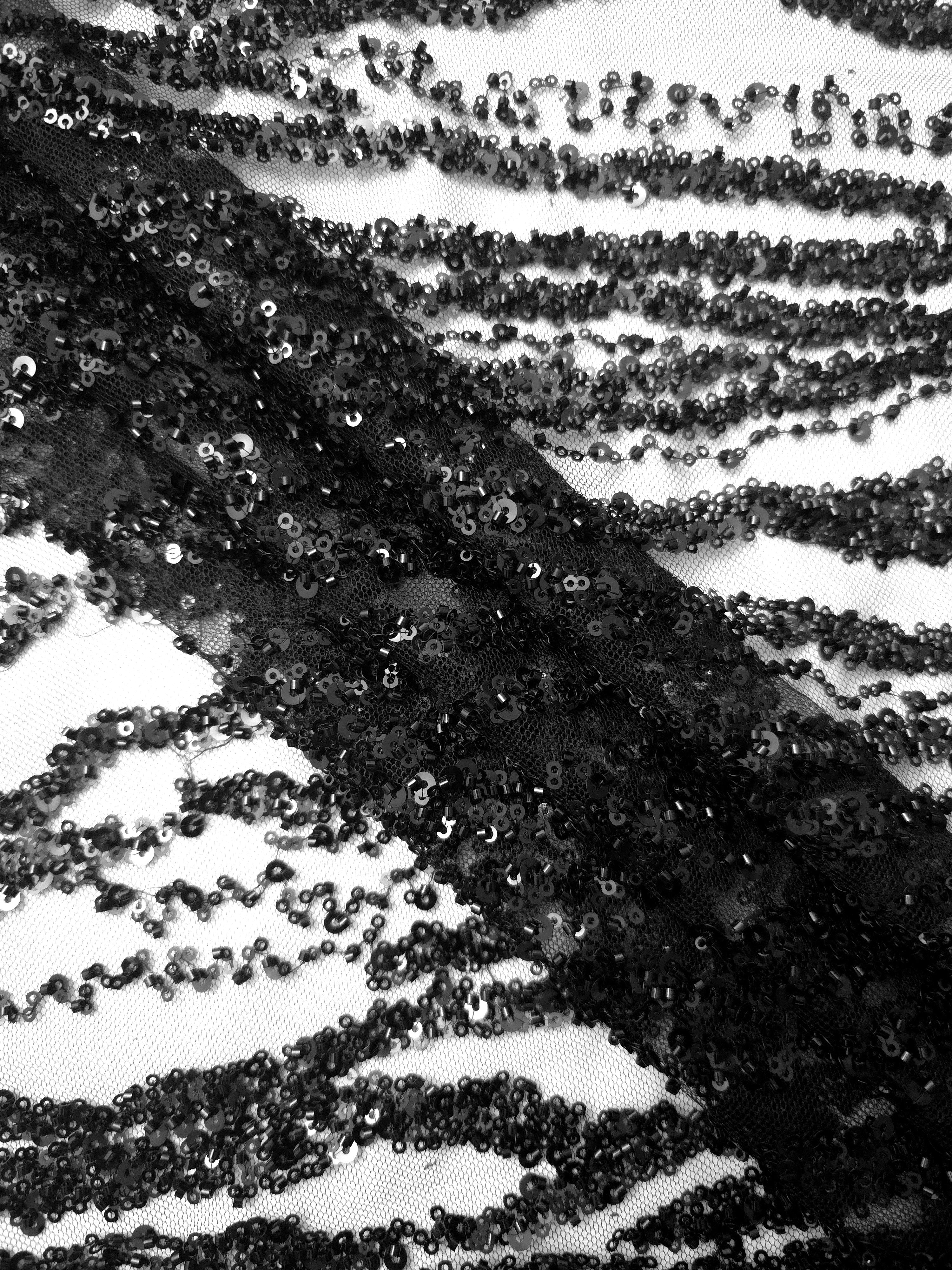 Macro of jet-black sequins and raised embroidery in the Zebra Strata pattern, showing the textured lace surface.