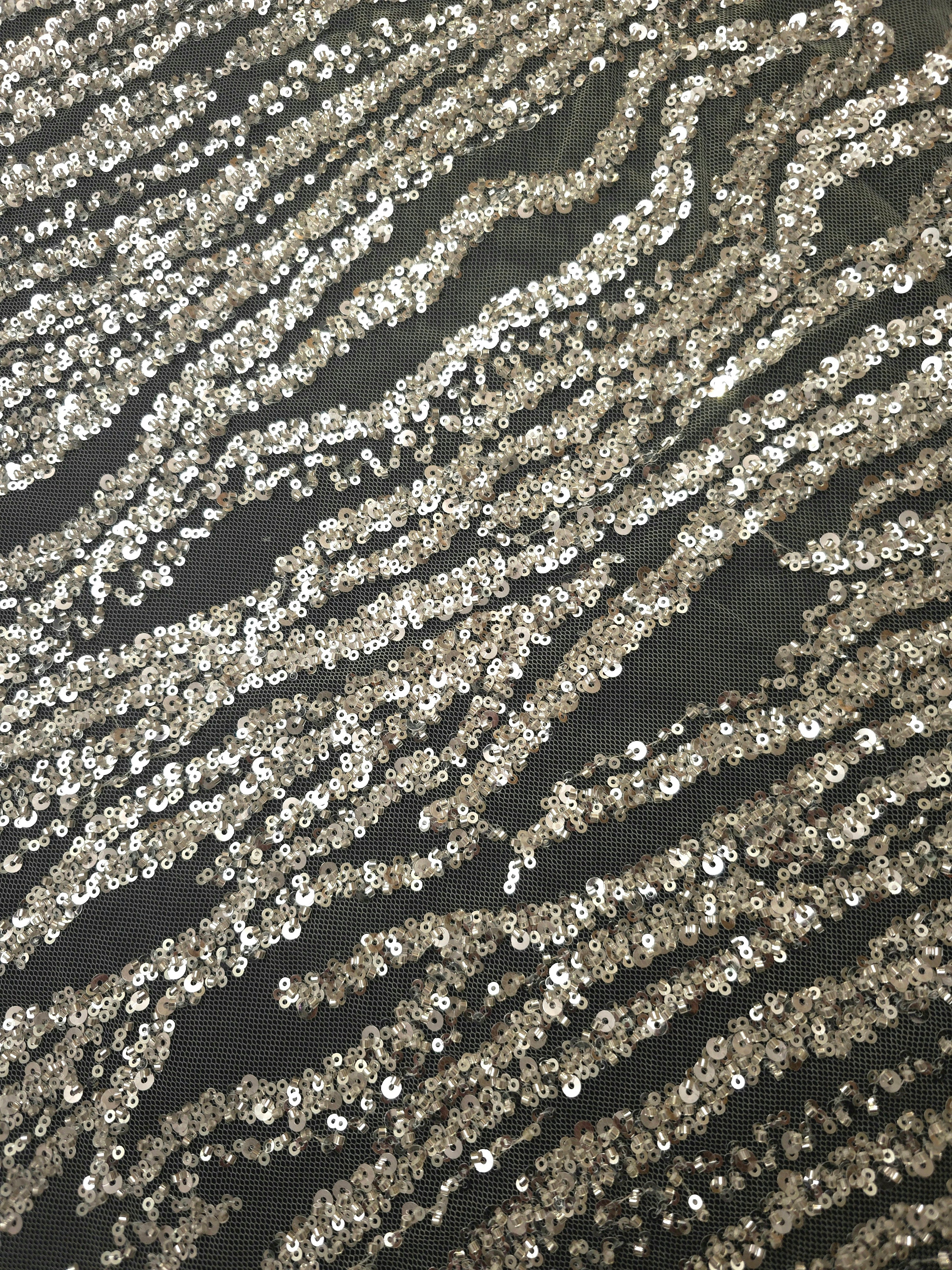 Diagonal detail of ivory-white sequin embroidery forming organic zebra-like bands across fine net fabric.