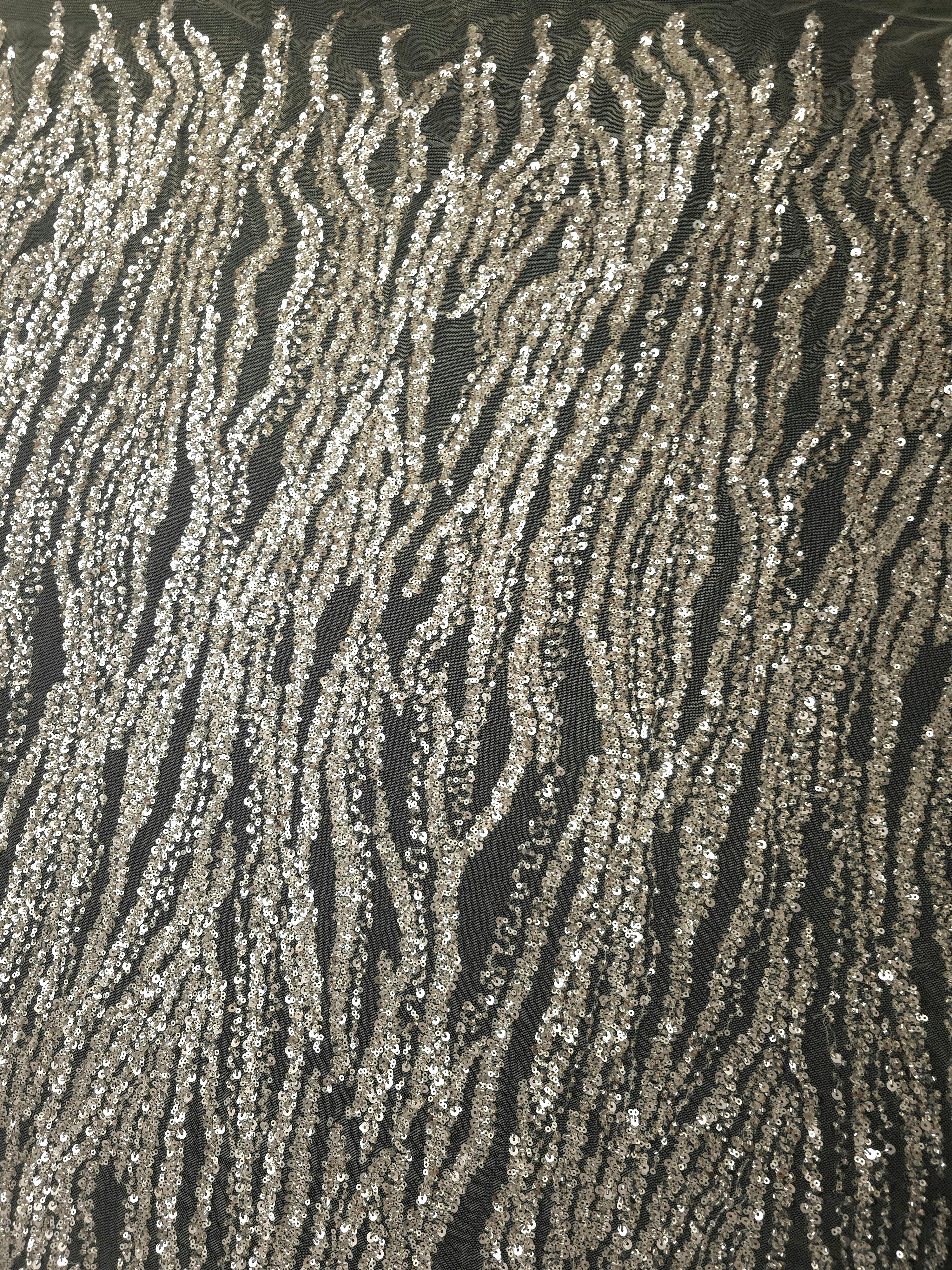 Vertical view of pearl white embellished lace with continuous rippling embroidery lines and reflective bead accents.
