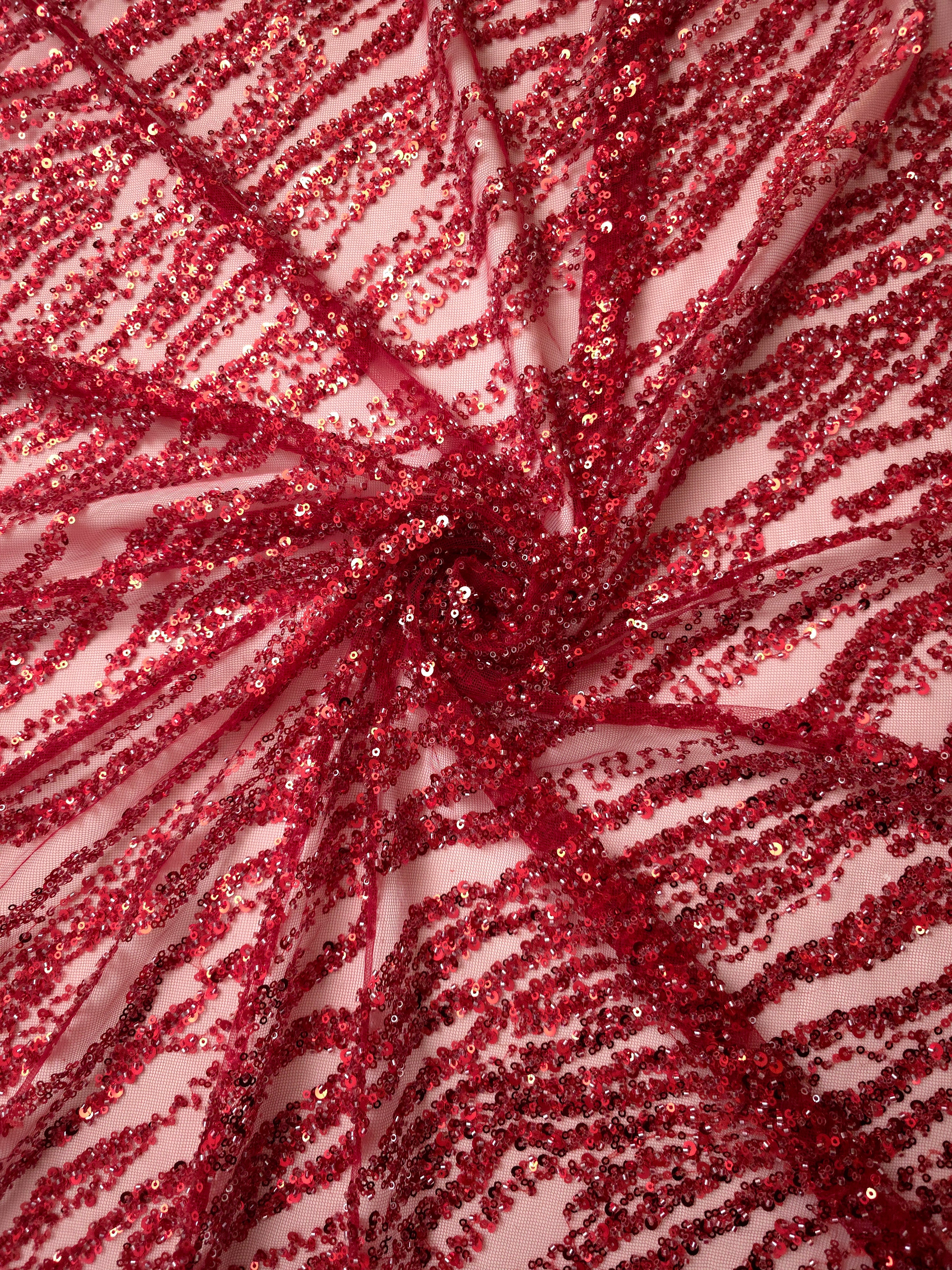 Gathered crimson couture lace with densely spaced embroidery ripples and beadwork following the folds.