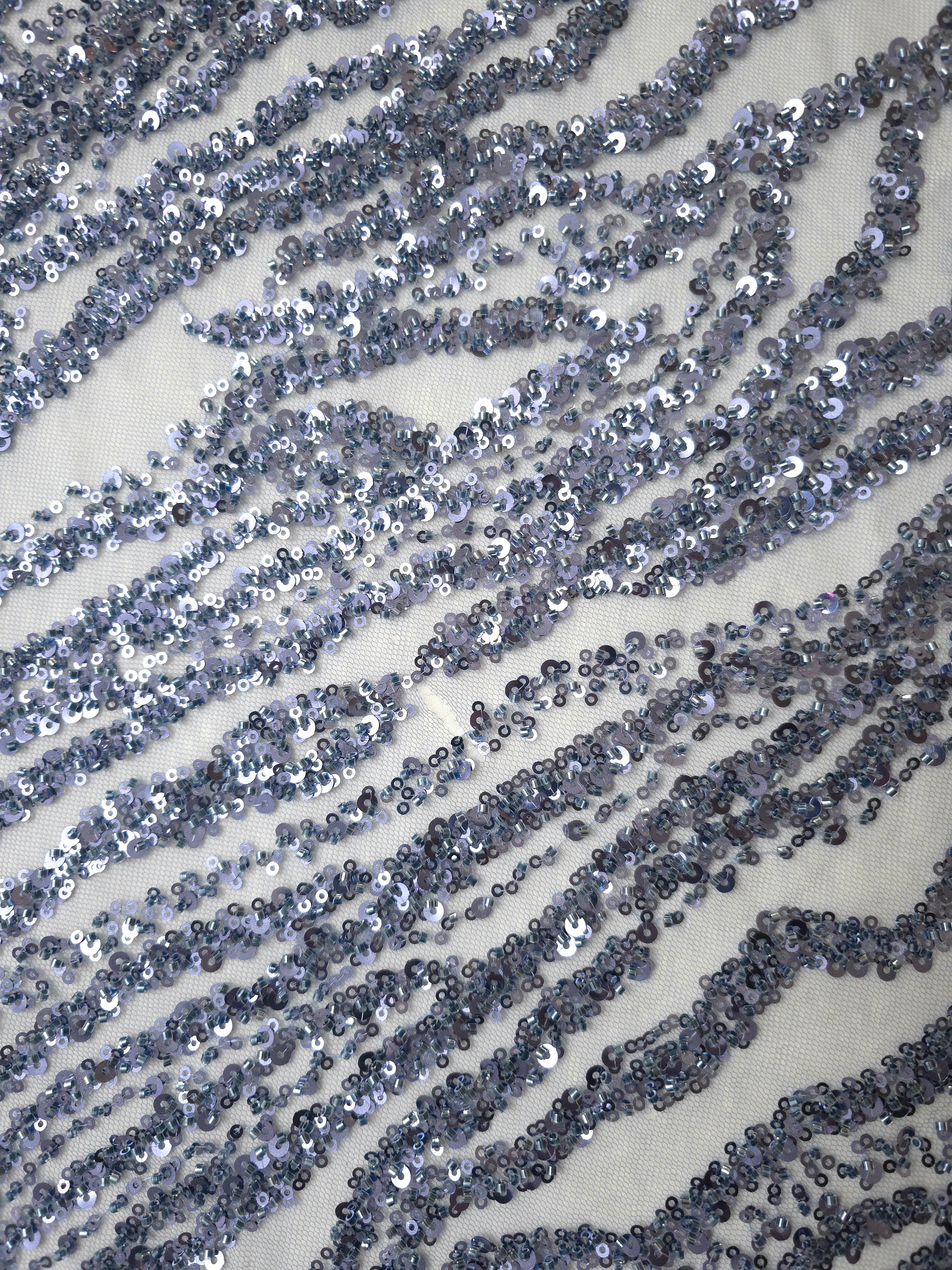 Diagonal detail of slate-blue zebra-style embroidered stripes with glittering accents and open mesh gaps.