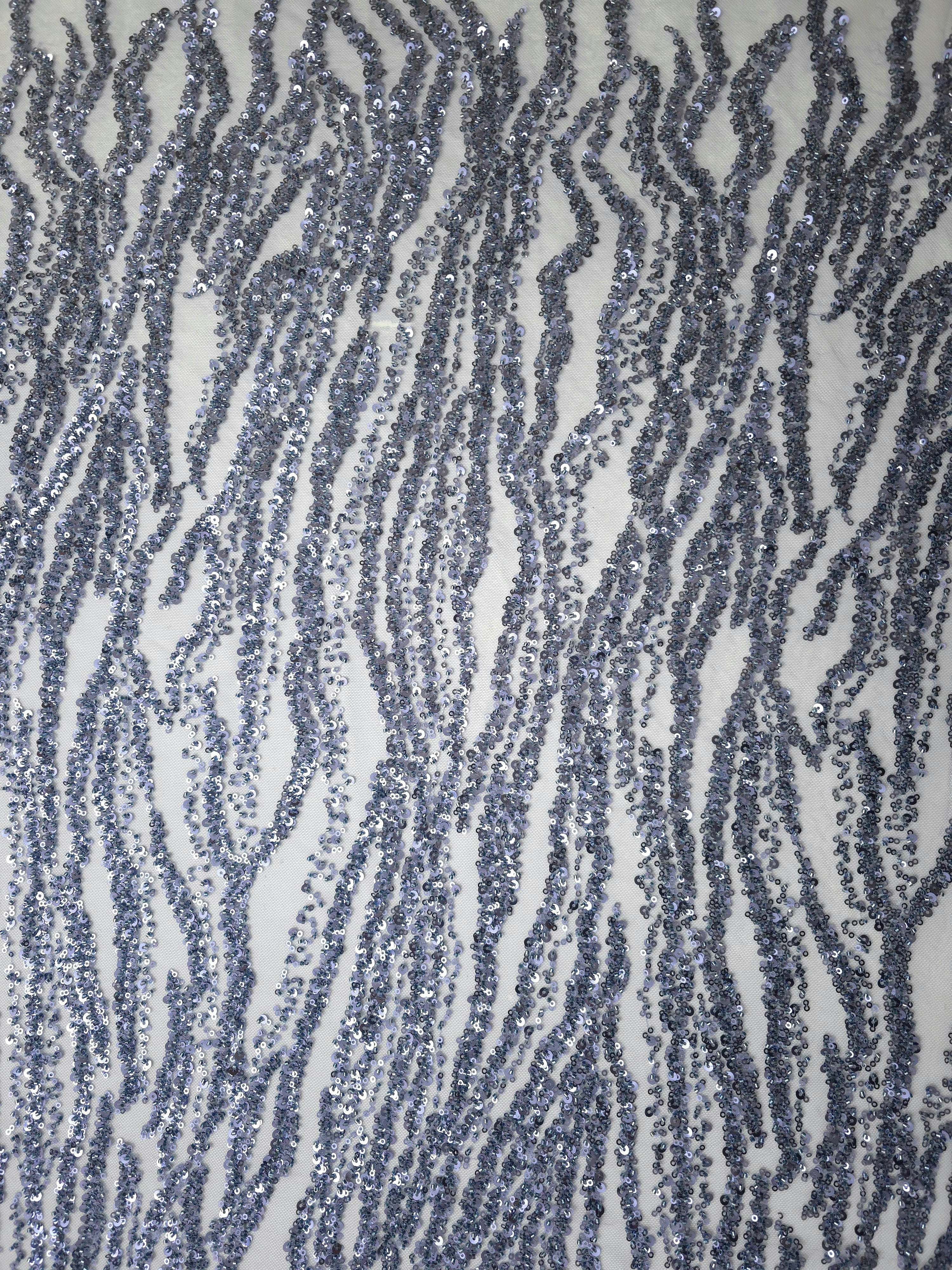 Portrait photograph showing the lengthwise repeat of undulating twilight blue beadwork on embroidered net.