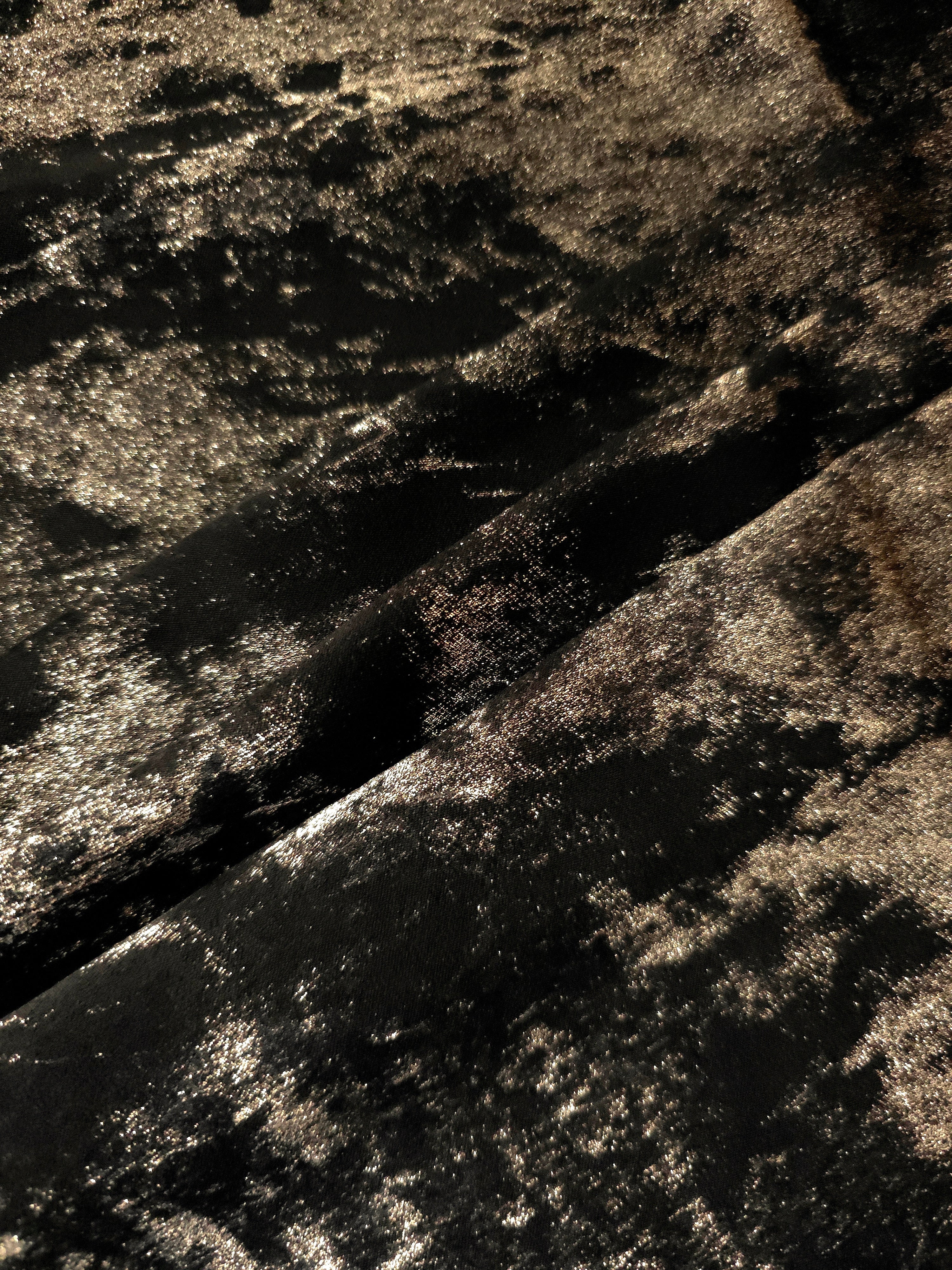 Black Bronze Lurex Italiano fabric in diagonal folds showing metallic sheen and drape for eveningwear.