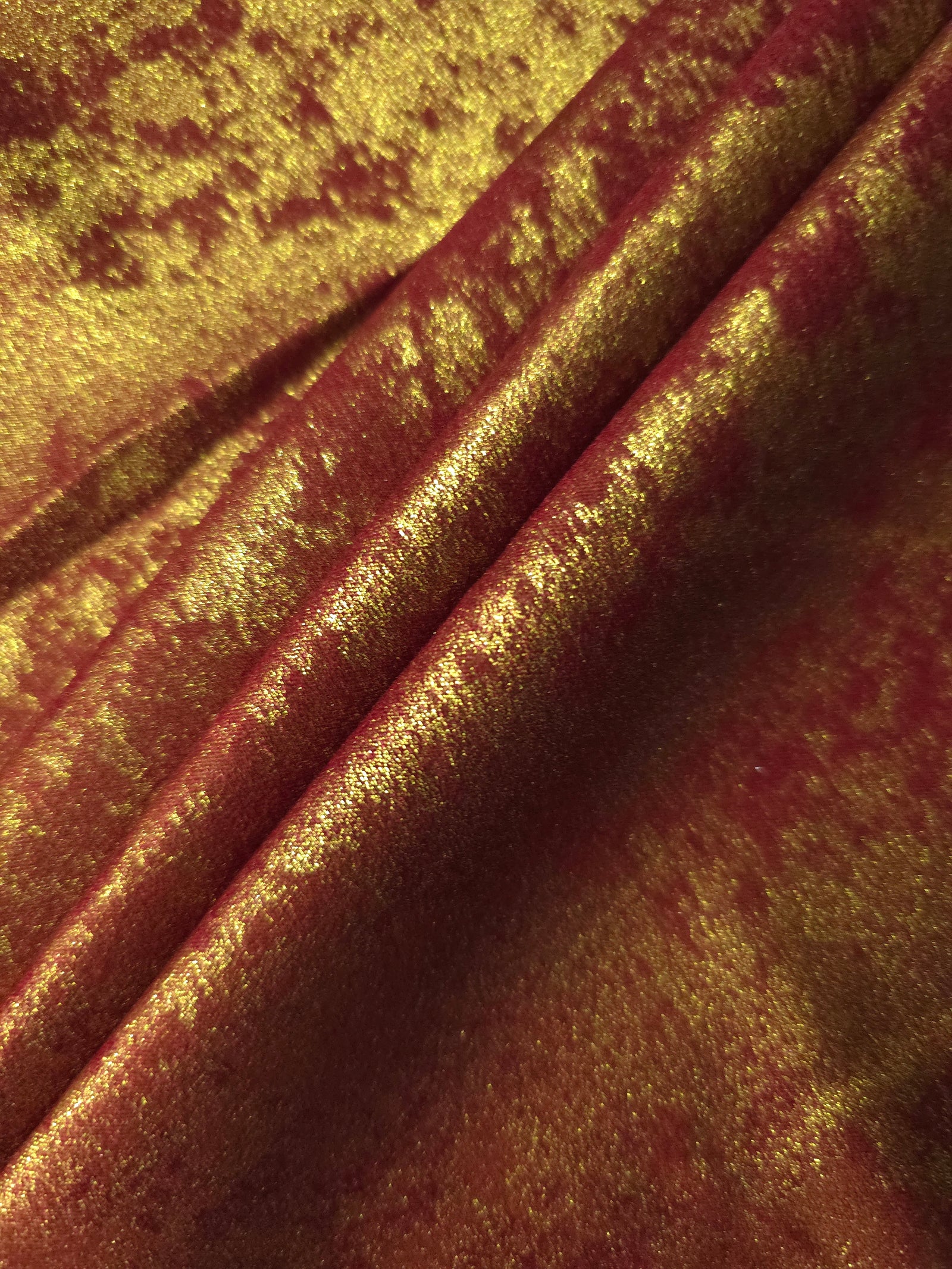 Burgundy Gold Lurex Italiano fabric in diagonal folds showing metallic sheen and drape for eveningwear.