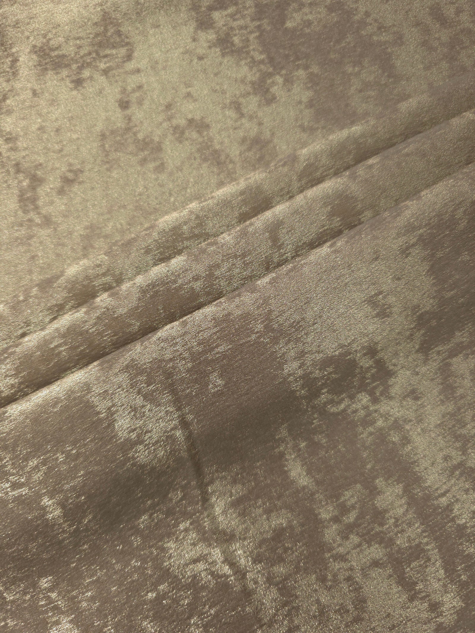 Champagne Taupe Lurex Italiano fabric in diagonal folds showing metallic sheen and drape for eveningwear.