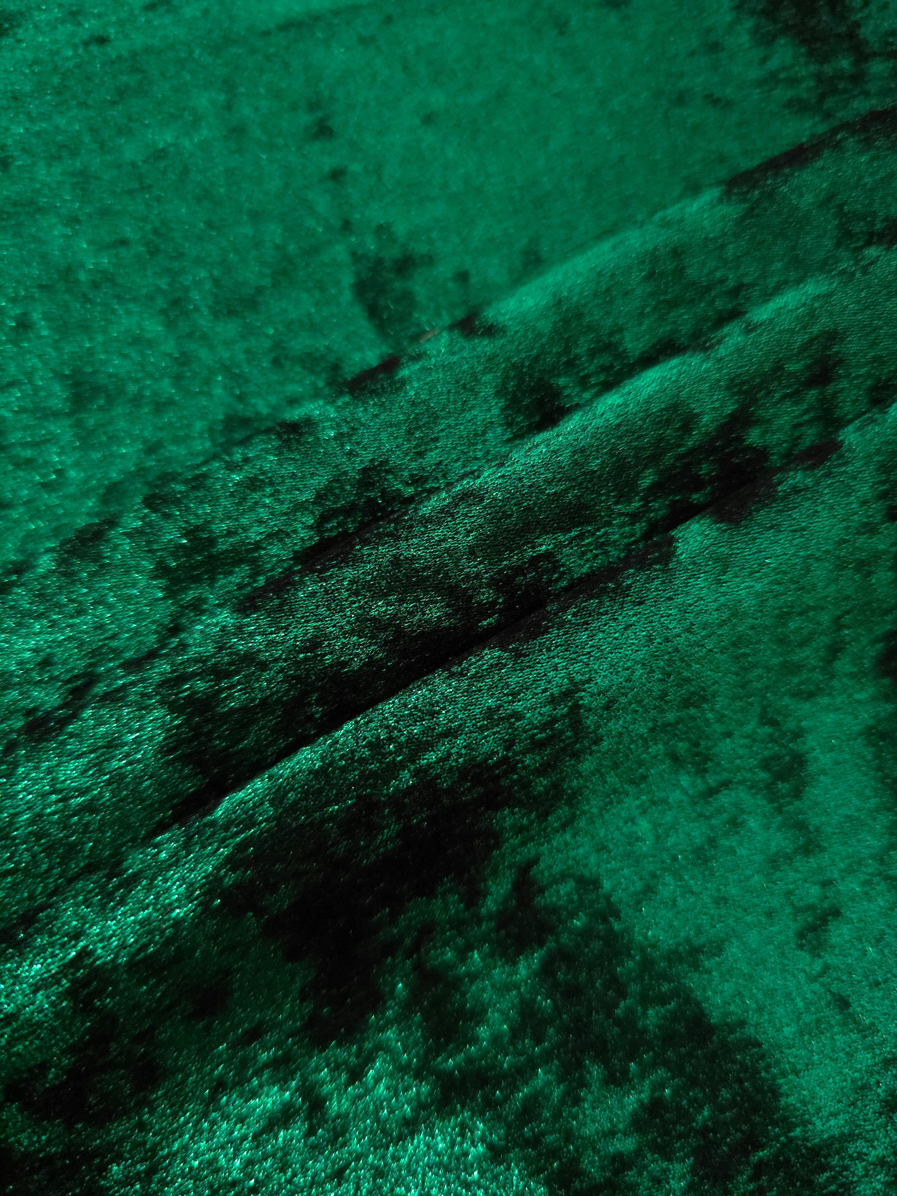 Emerald Green Lurex Italiano fabric in diagonal folds showing metallic sheen and drape for eveningwear.