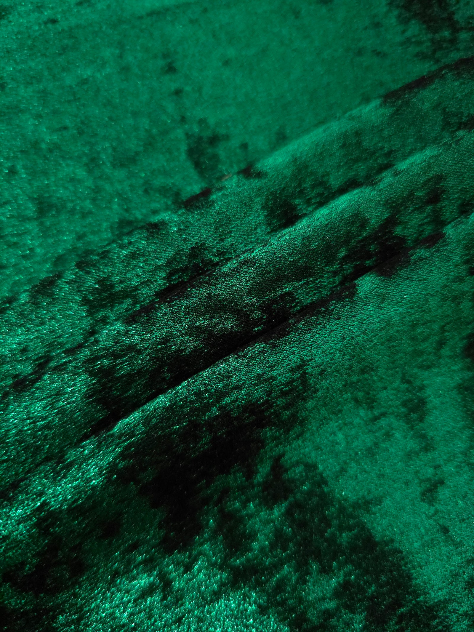 Emerald Green Lurex Italiano fabric in diagonal folds showing metallic sheen and drape for eveningwear.