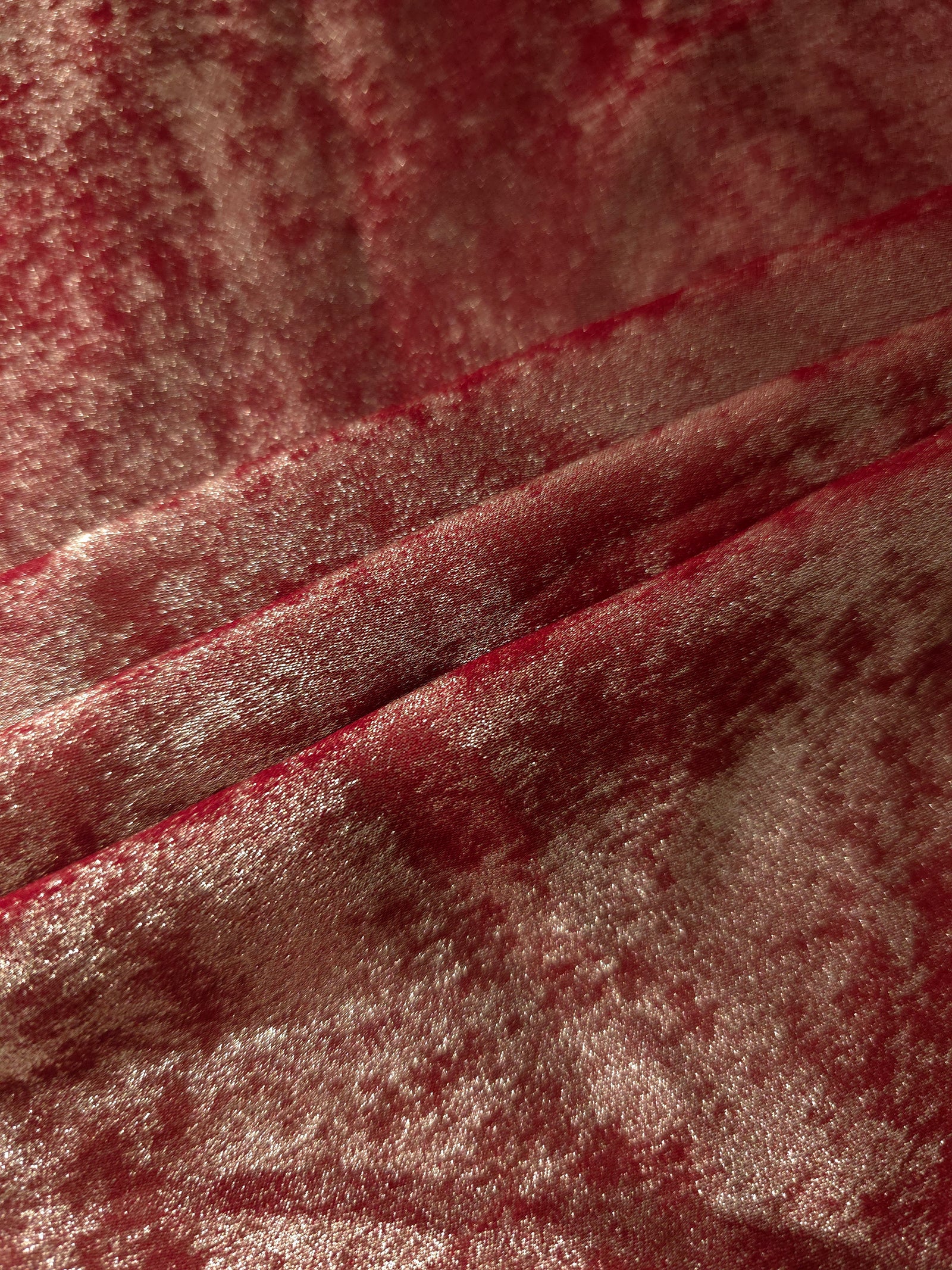 Garnet Rose Lurex Italiano fabric in diagonal folds showing metallic sheen and drape for eveningwear.