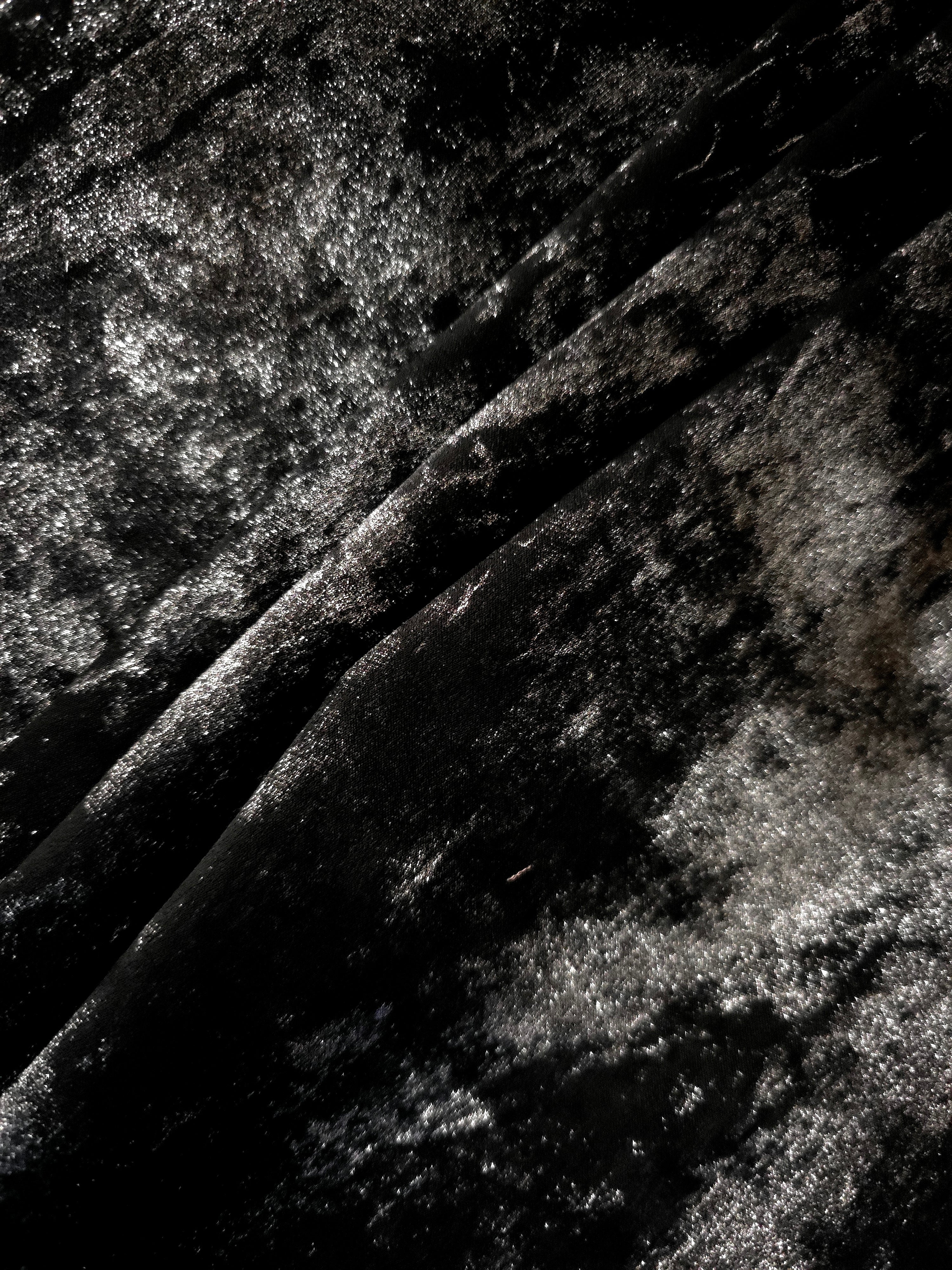 Jet Black Lurex Italiano fabric in diagonal folds showing metallic sheen and drape for eveningwear.