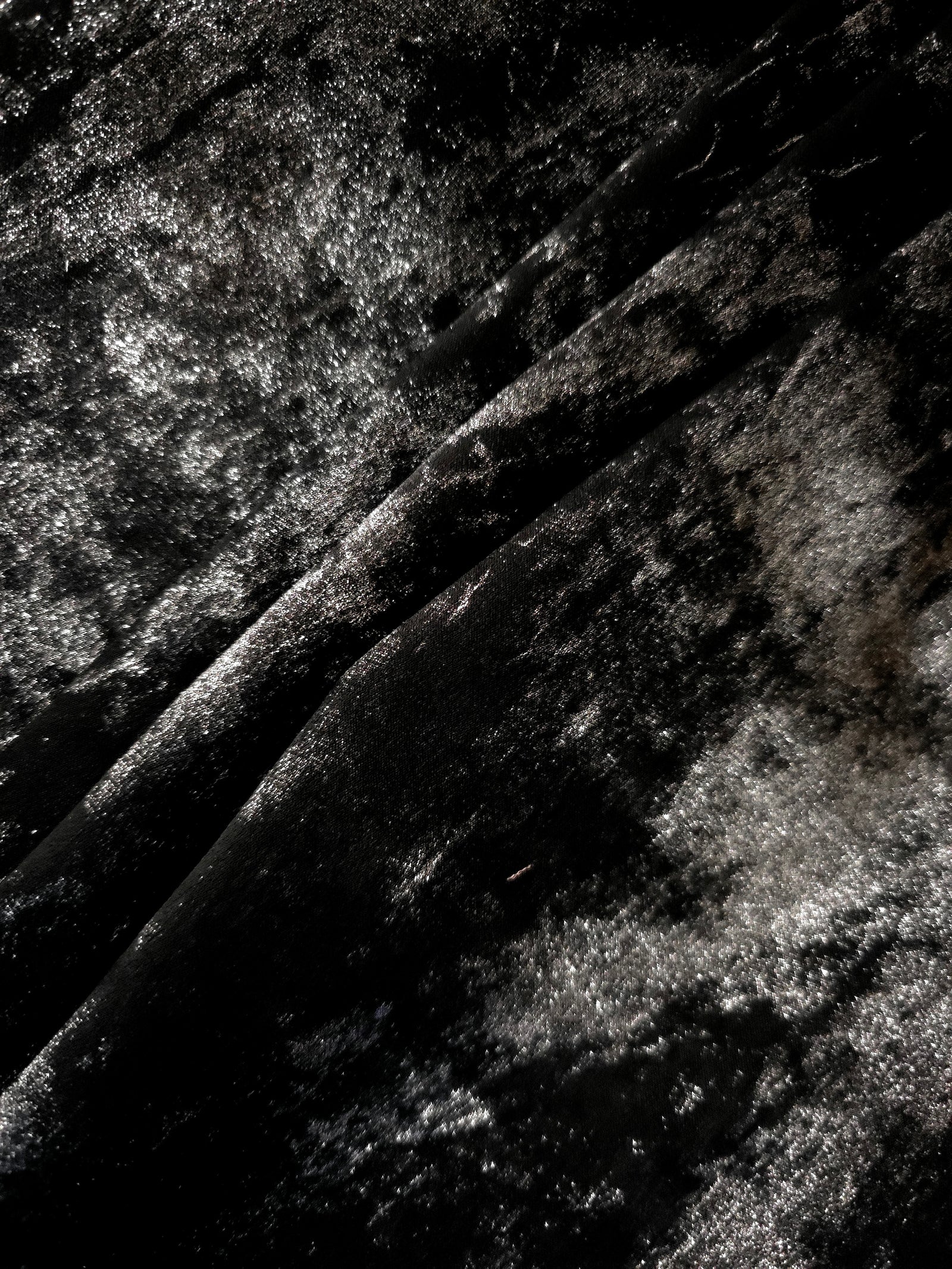Jet Black Lurex Italiano fabric in diagonal folds showing metallic sheen and drape for eveningwear.