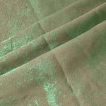 Mint Sage Lurex Italiano fabric in diagonal folds showing metallic sheen and drape for eveningwear.