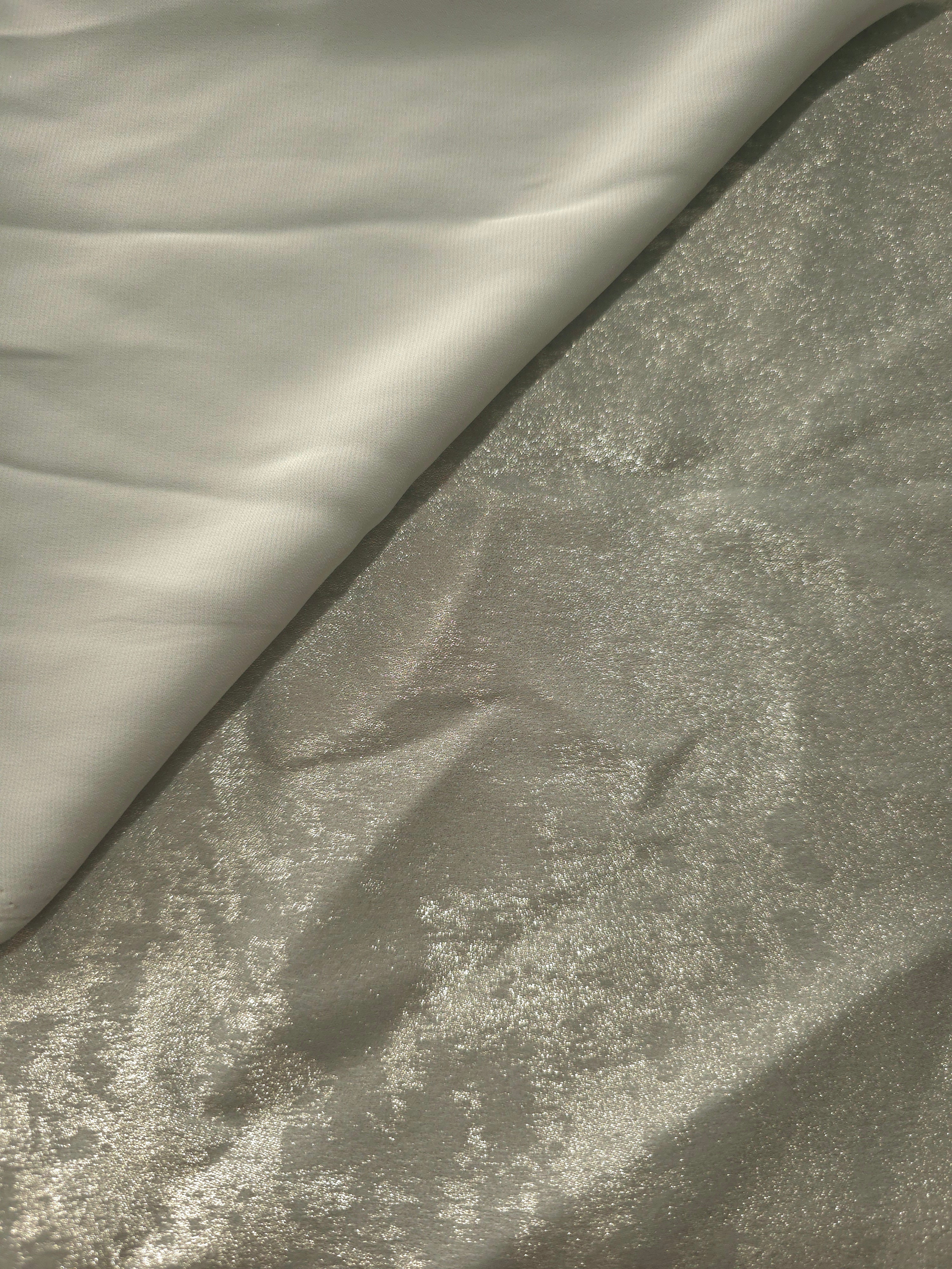 Pearl Silver Lurex Italiano fabric in diagonal folds showing metallic sheen and drape for eveningwear.