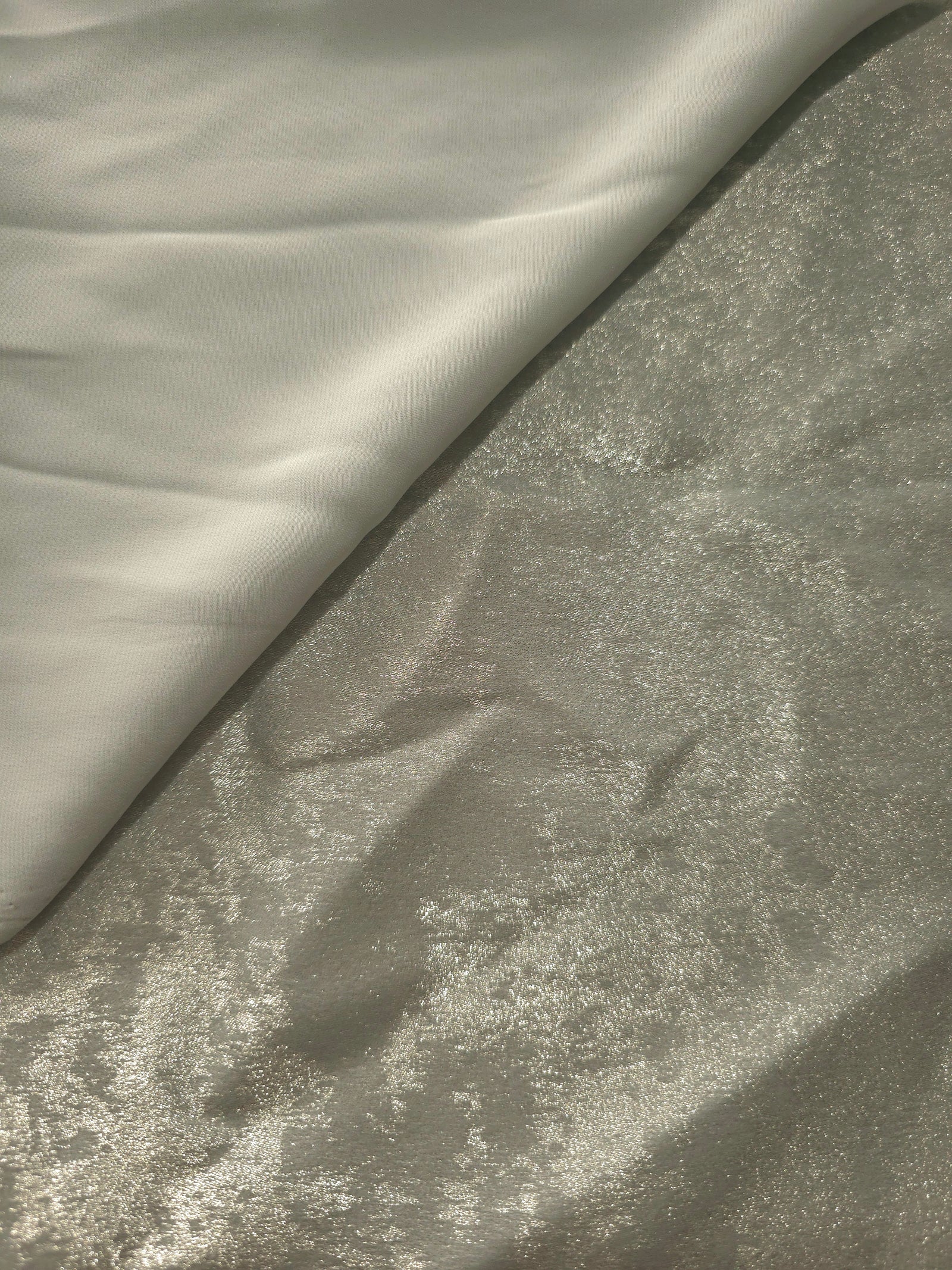 Pearl Silver Lurex Italiano fabric in diagonal folds showing metallic sheen and drape for eveningwear.