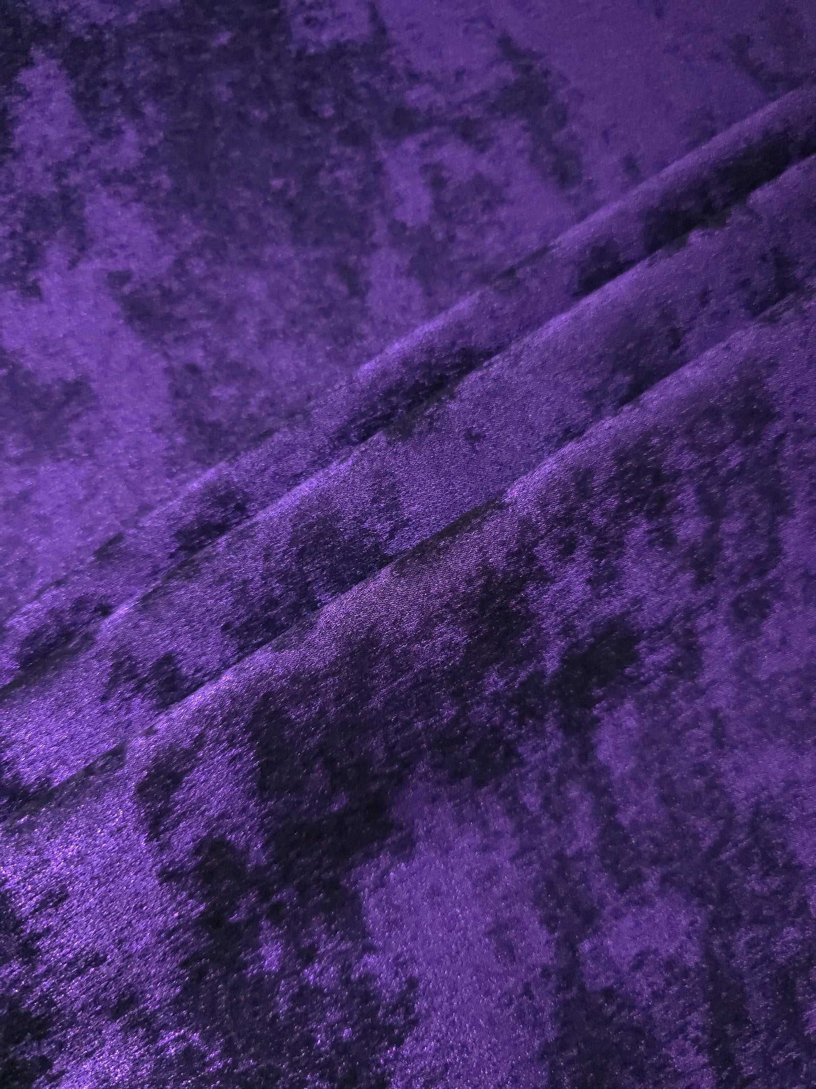 Royal Purple Lurex Italiano fabric in diagonal folds showing metallic sheen and drape for eveningwear.