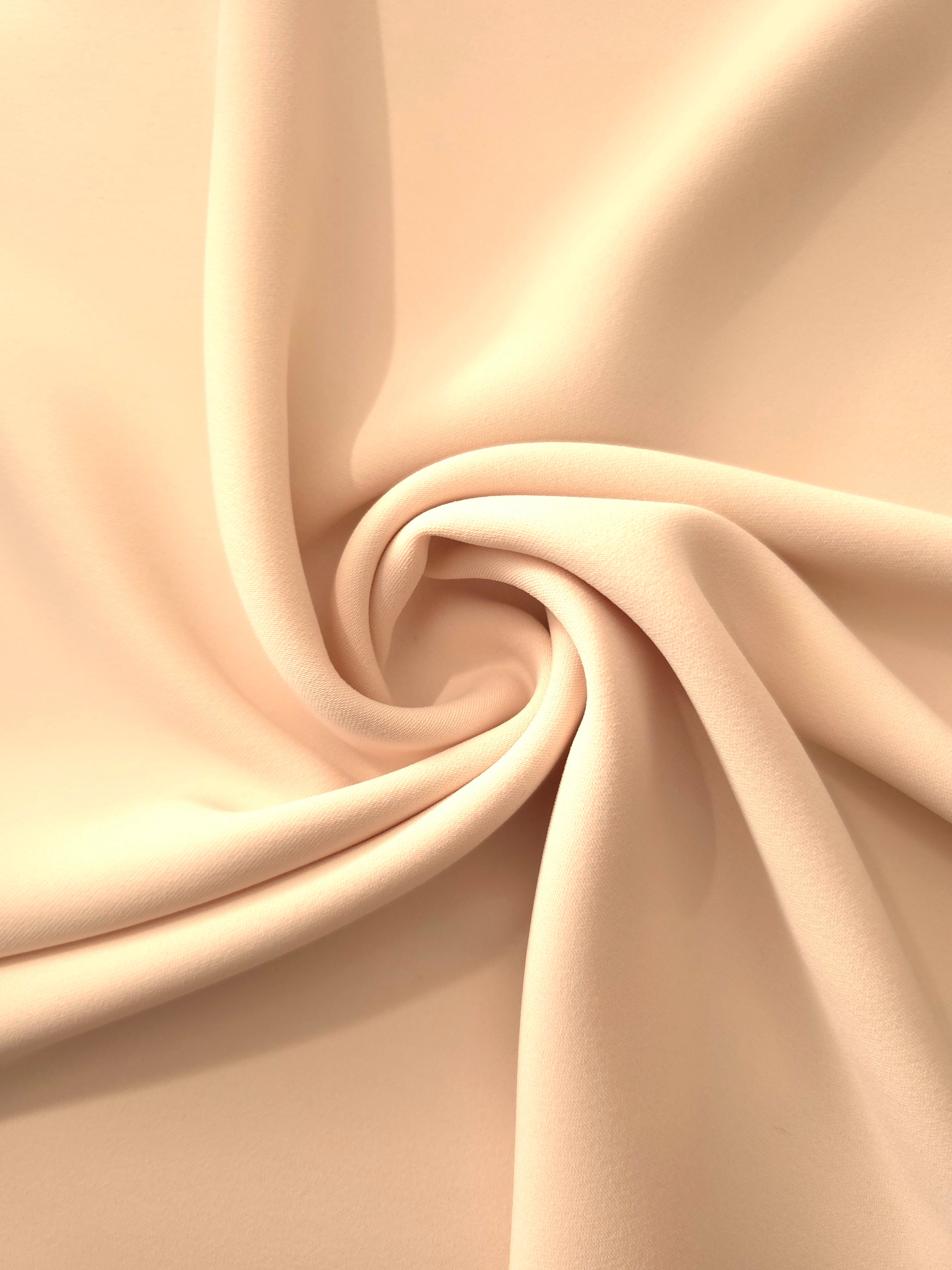 Swirled Apricot Nude Silky Italian Crepe showing flowing movement in a swirl drape, versatile for cocktail dresses, skirts and polished separates.