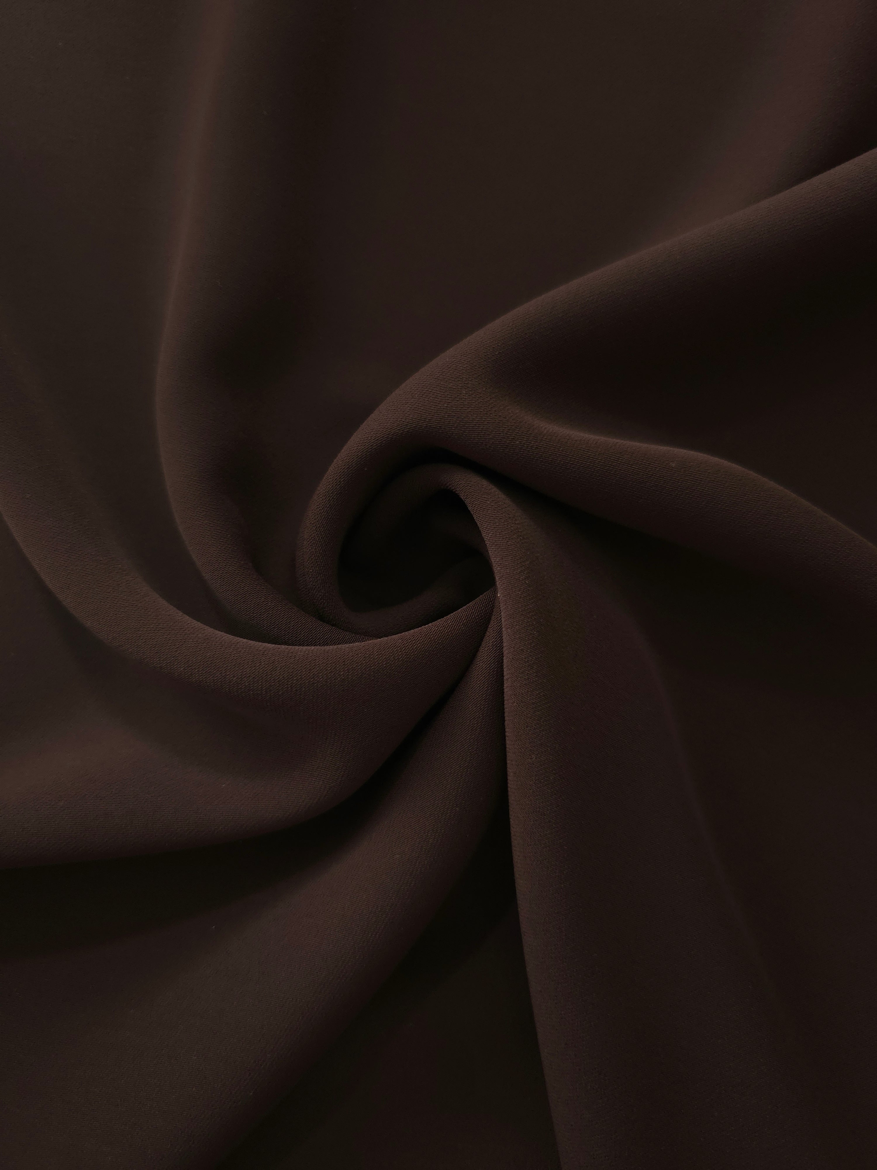 Swirled Black Cocoa Silky Italian Crepe showing flowing movement in a swirl drape, versatile for evening dresses, flowing skirts and occasionwear tops.