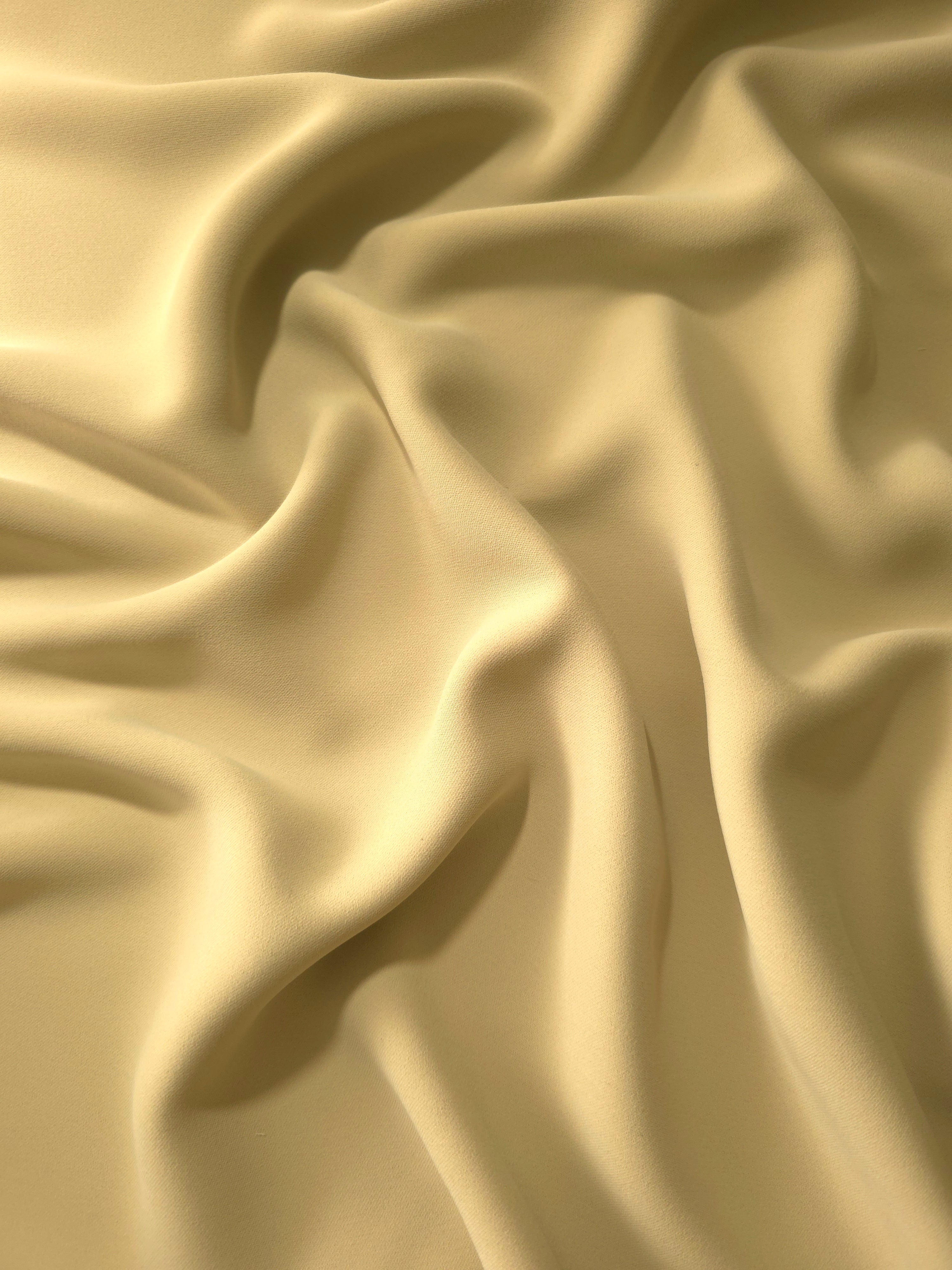 Draped Buttercream Gold Silky Italian Crepe showing an elegant fall through draped folds, ideal for office blouses, tailored dresses and soft jackets.