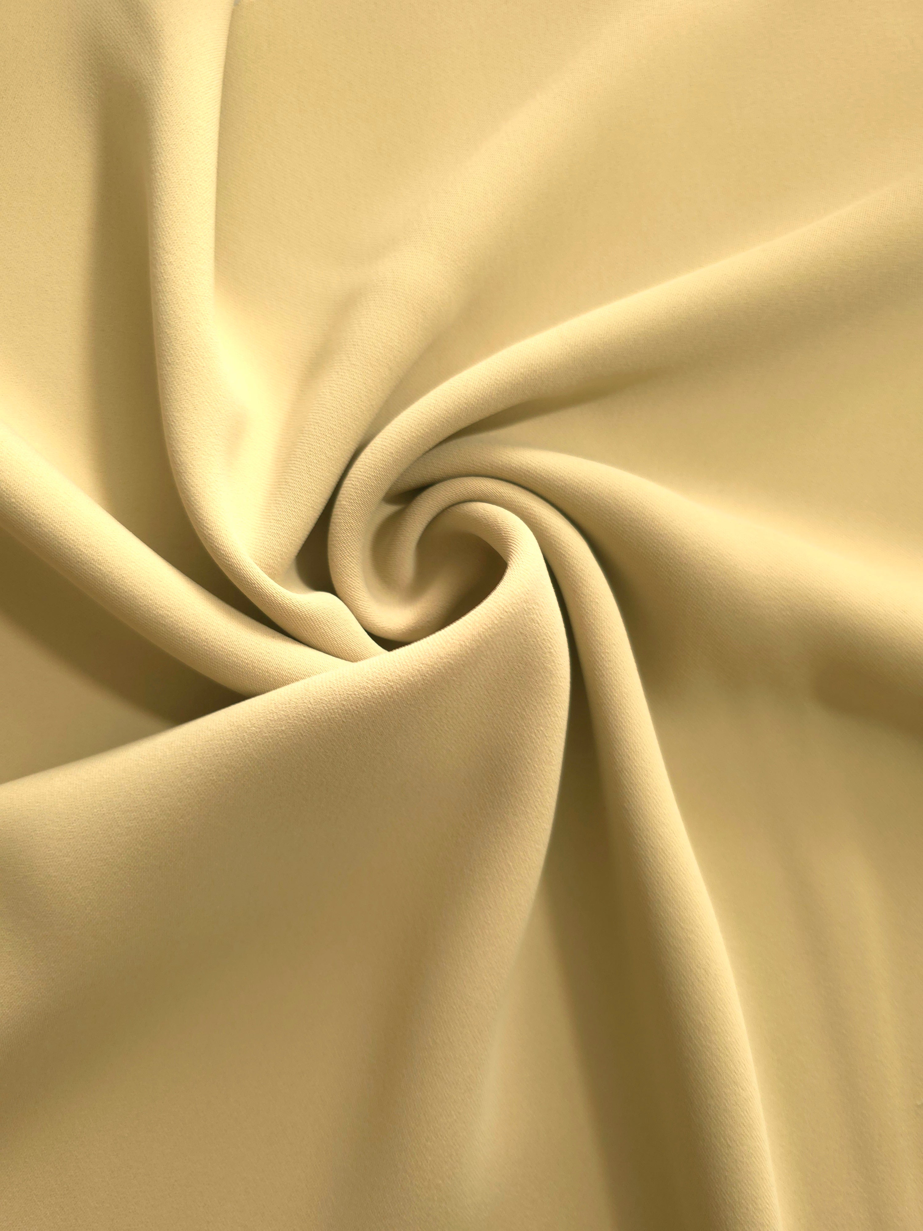 Swirled Buttercream Gold Silky Italian Crepe showing flowing movement in a swirl drape, versatile for kaftans, long skirts and fluid occasionwear.