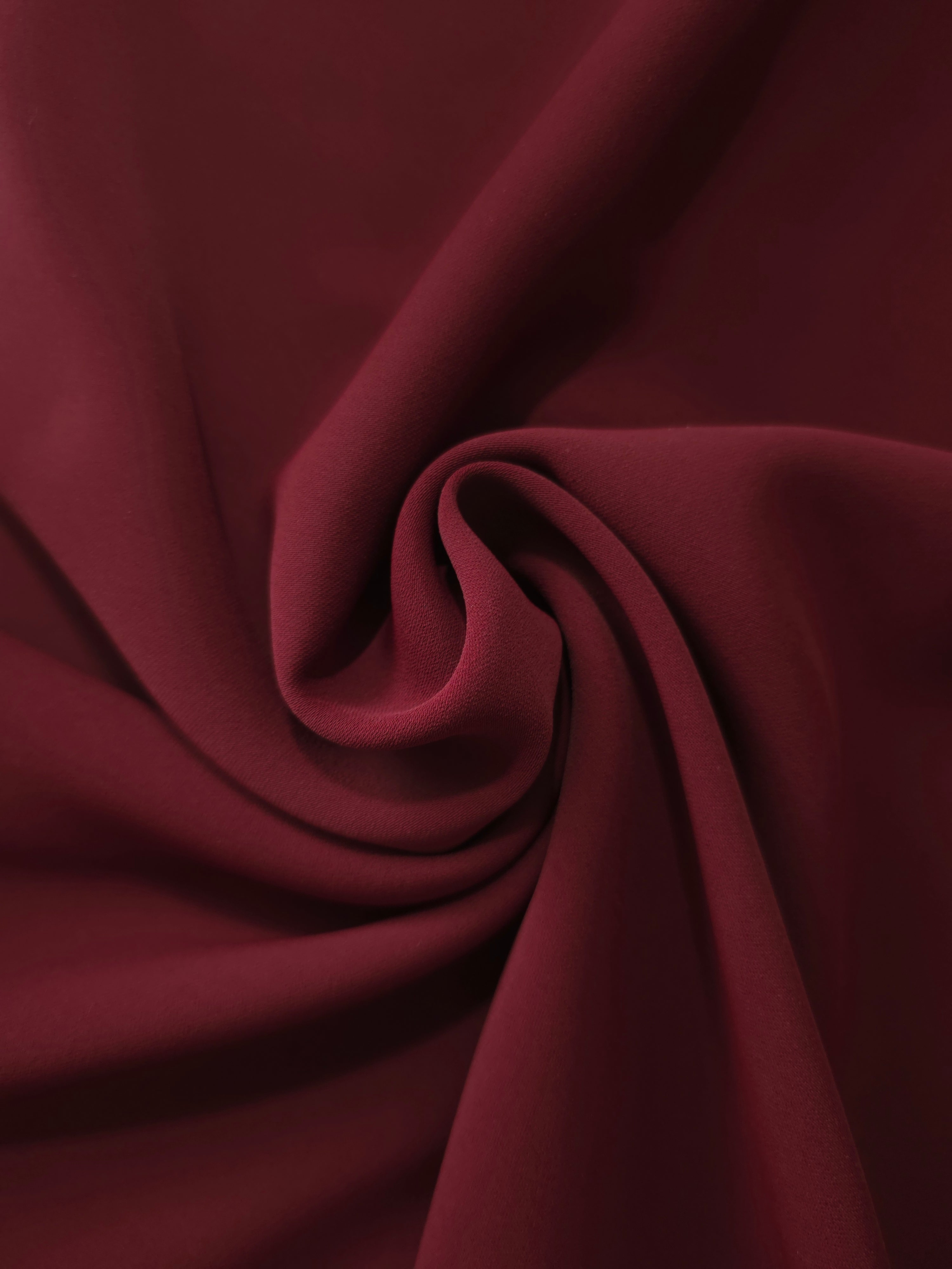Swirled Garnet Wine Silky Italian Crepe showing flowing movement in a swirl drape, versatile for cocktail dresses, skirts and polished separates.